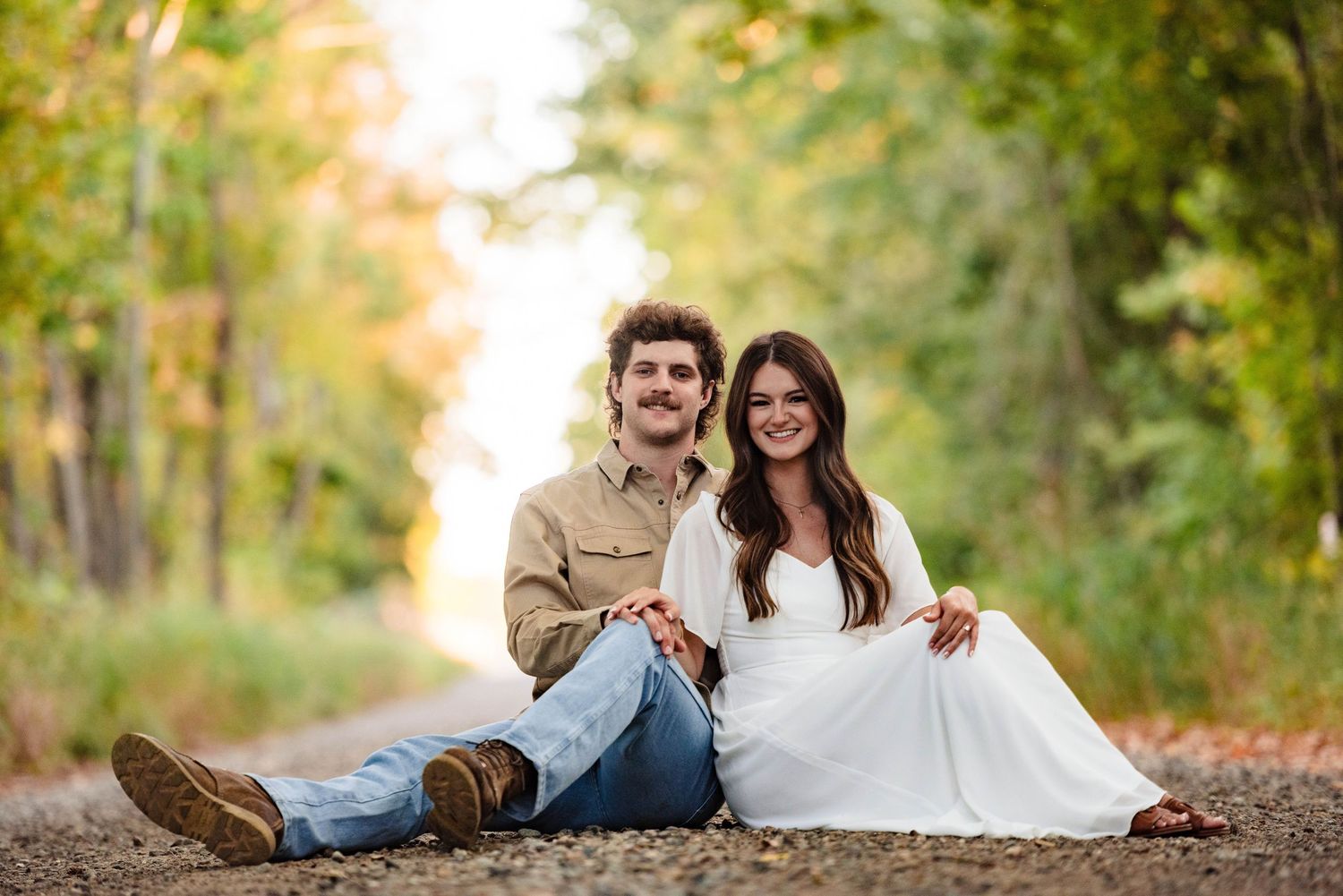 Couple sharing intimate moments on a tree-lined path during autumn.