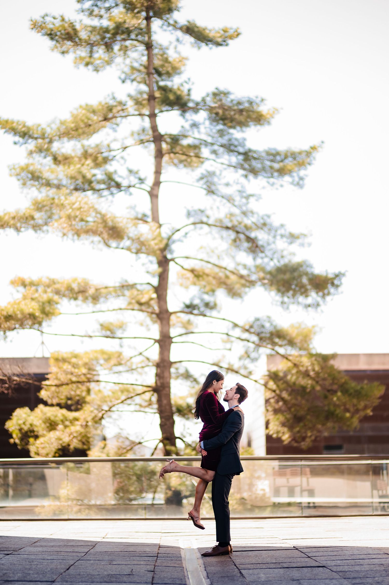 Silhouetted figures pose against tall pine trees during golden hour.