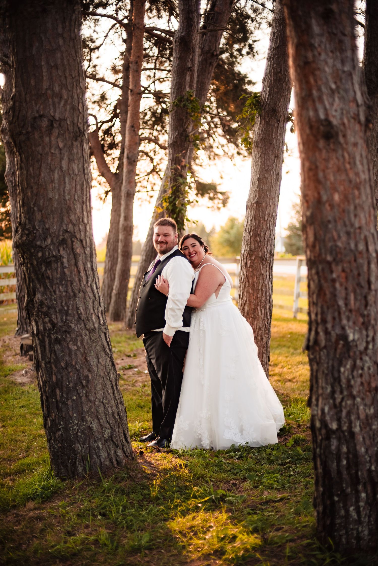 Romantic wedding portraits among tall pine trees at sunset with white dress flowing in golden light.