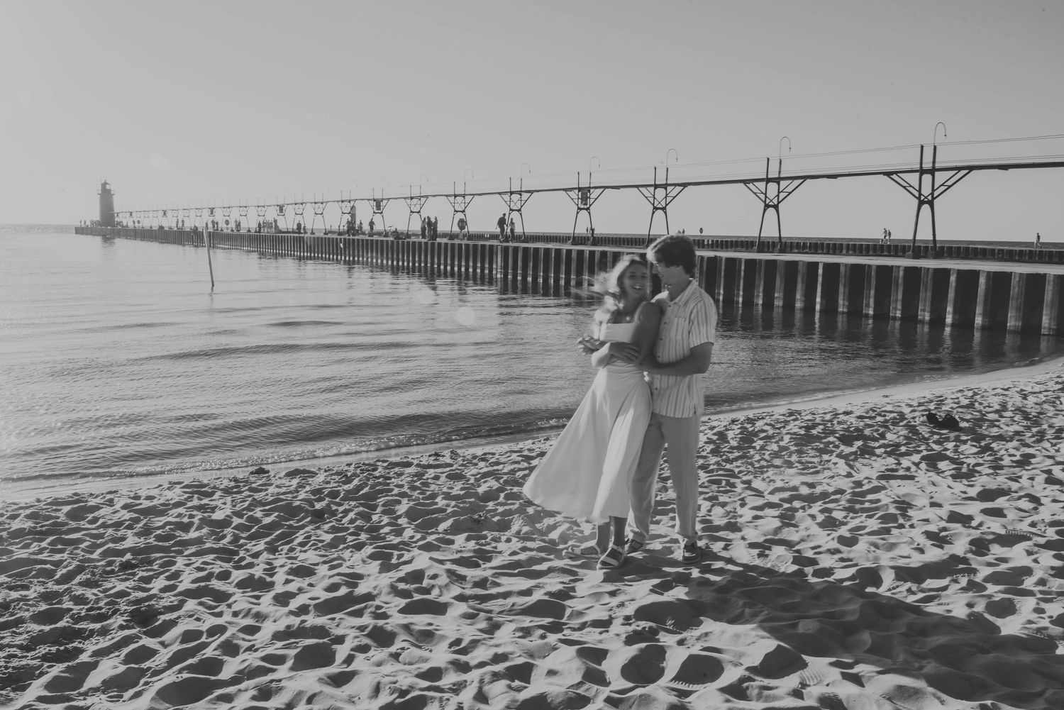 Couple walking along a pier at the beach with dramatic black and white tones.