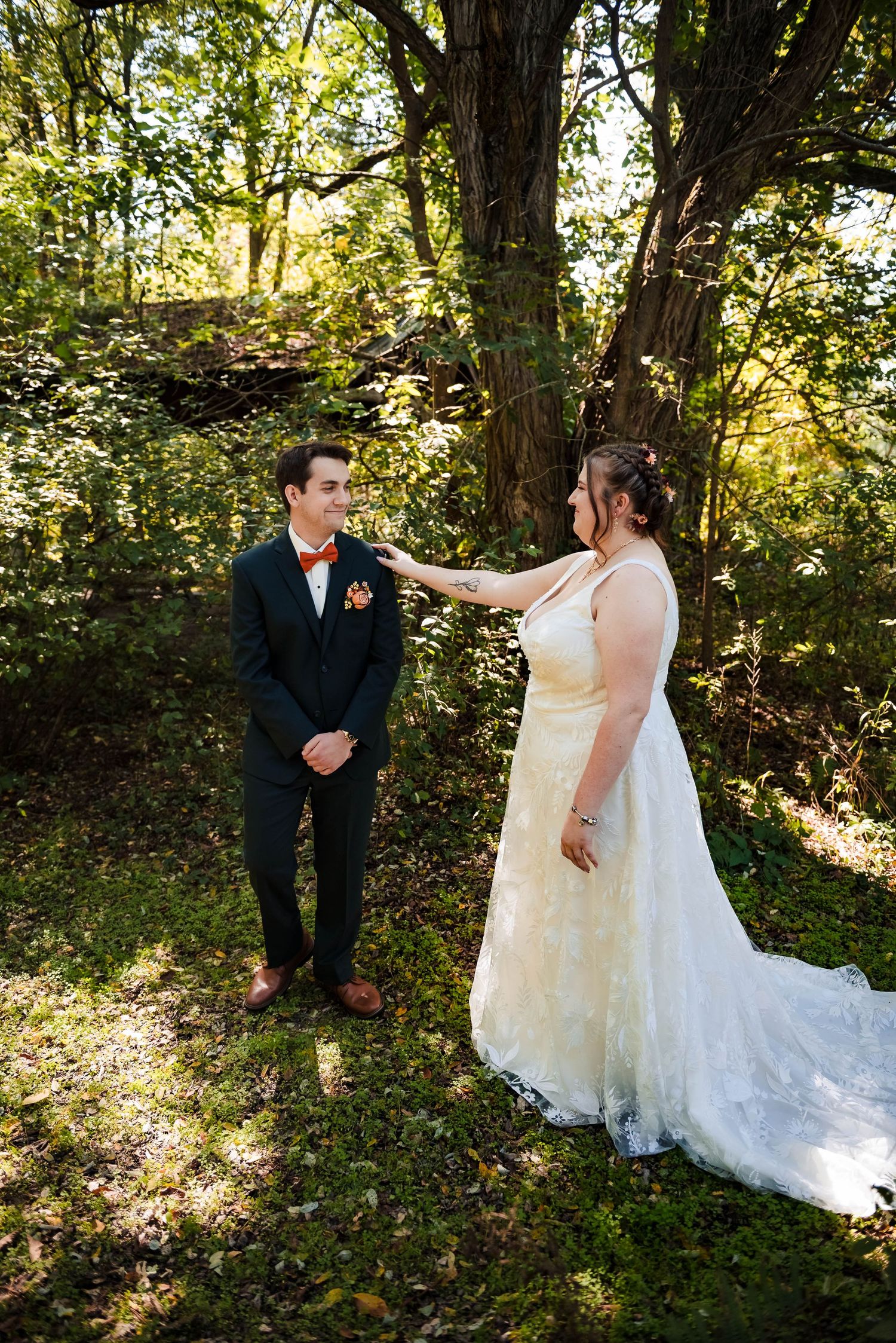 A couple shares their first look moment in a wooded setting during their autumn wedding.