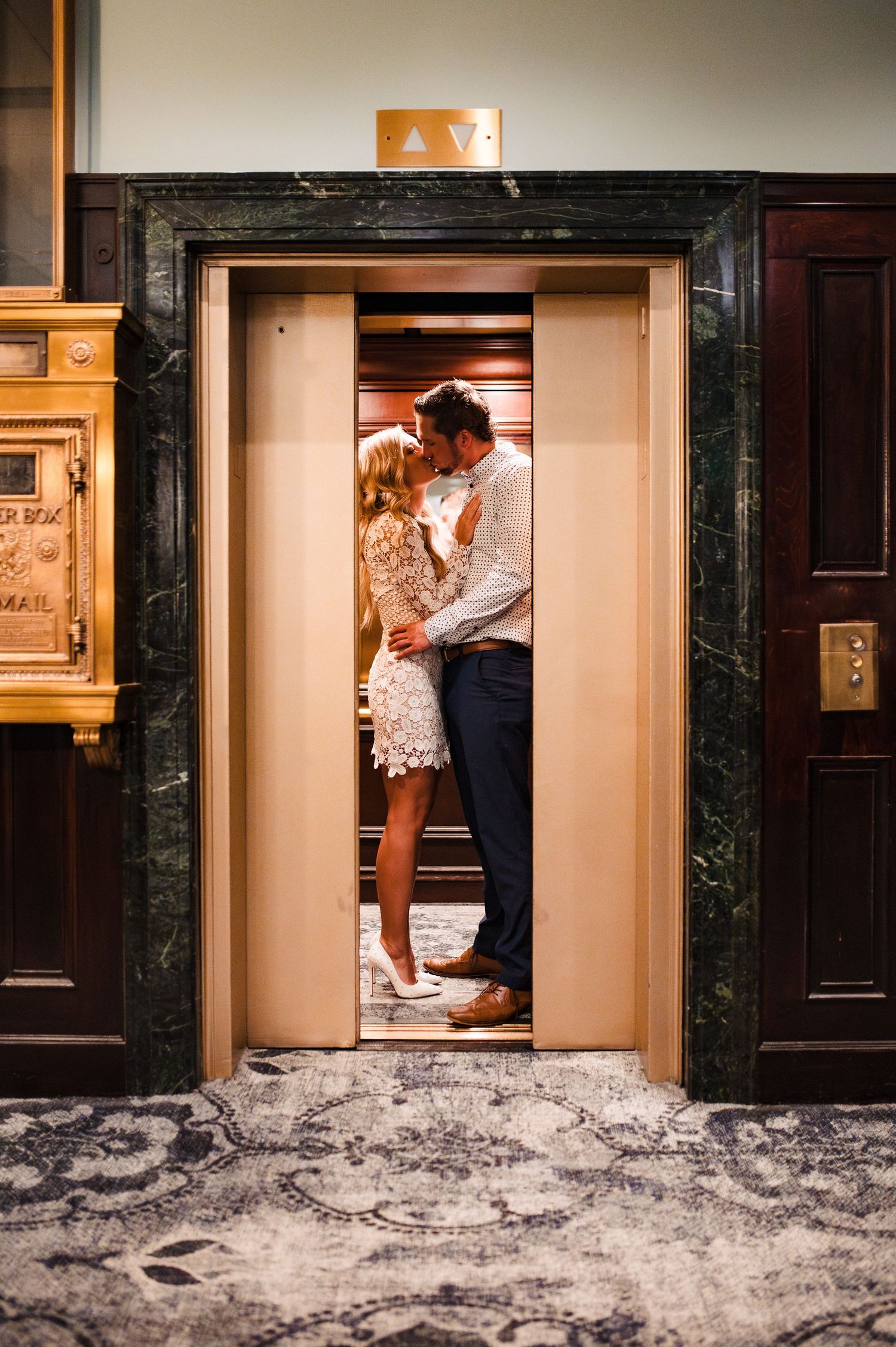 Romantic scene in an elevator with marble walls and dramatic lighting.