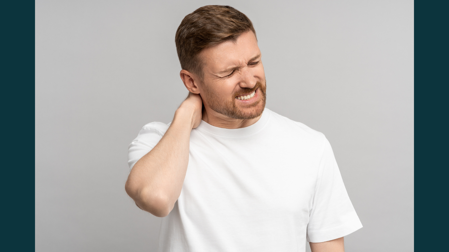 A man in a white t-shirt grimacing in pain while holding the back of his neck, illustrating symptoms of cervical discomfort.
