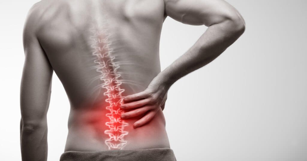 Person clutching lower back with red highlighted spine showing area of pain and inflammation.