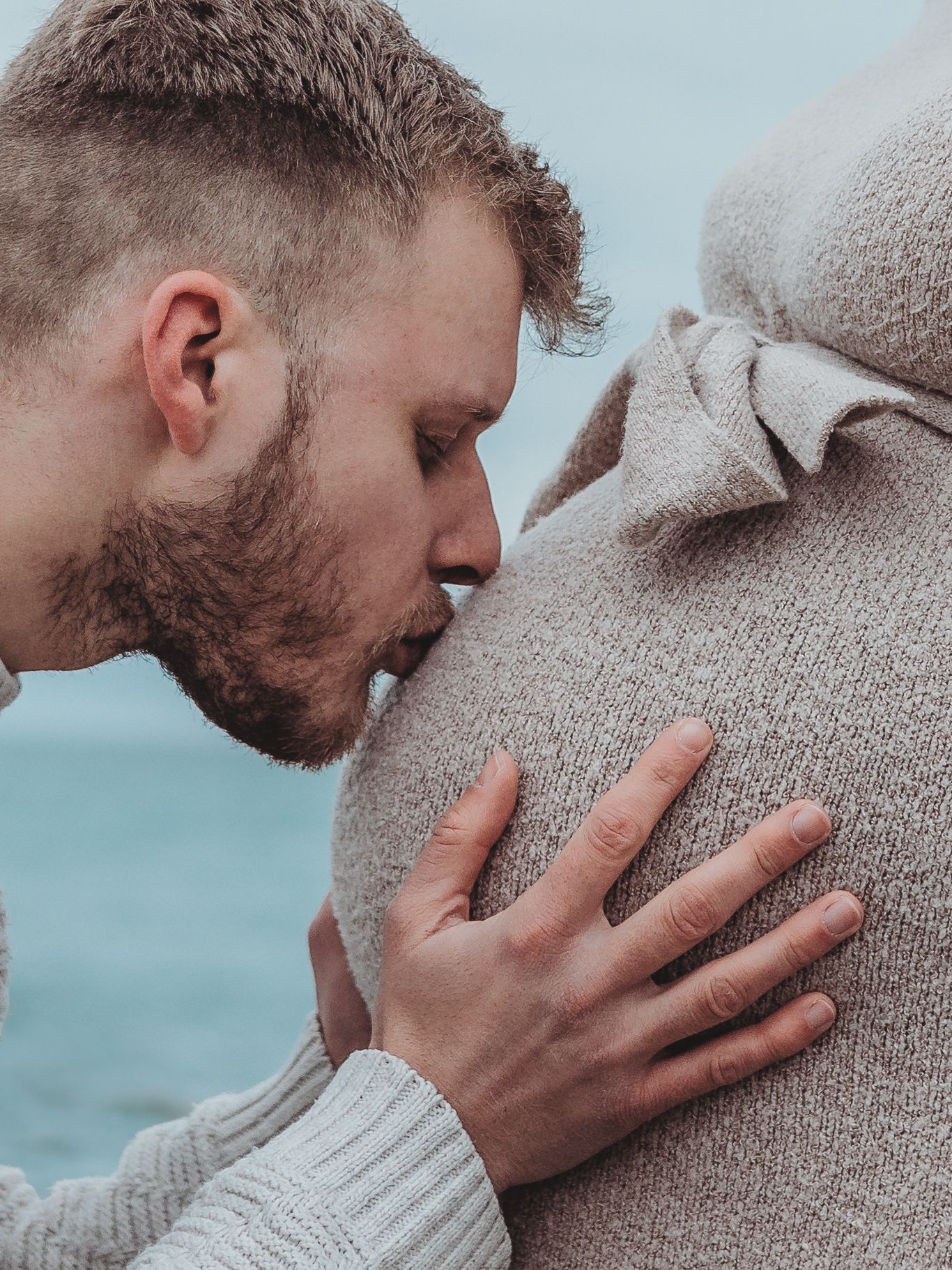 A series of intimate close-up photos showing tender moments between two people against an ocean backdrop.