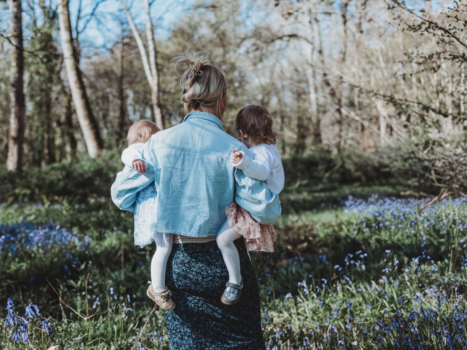 Two people walk through a spring woodland filled with blooming bluebells creating a magical natural scene.