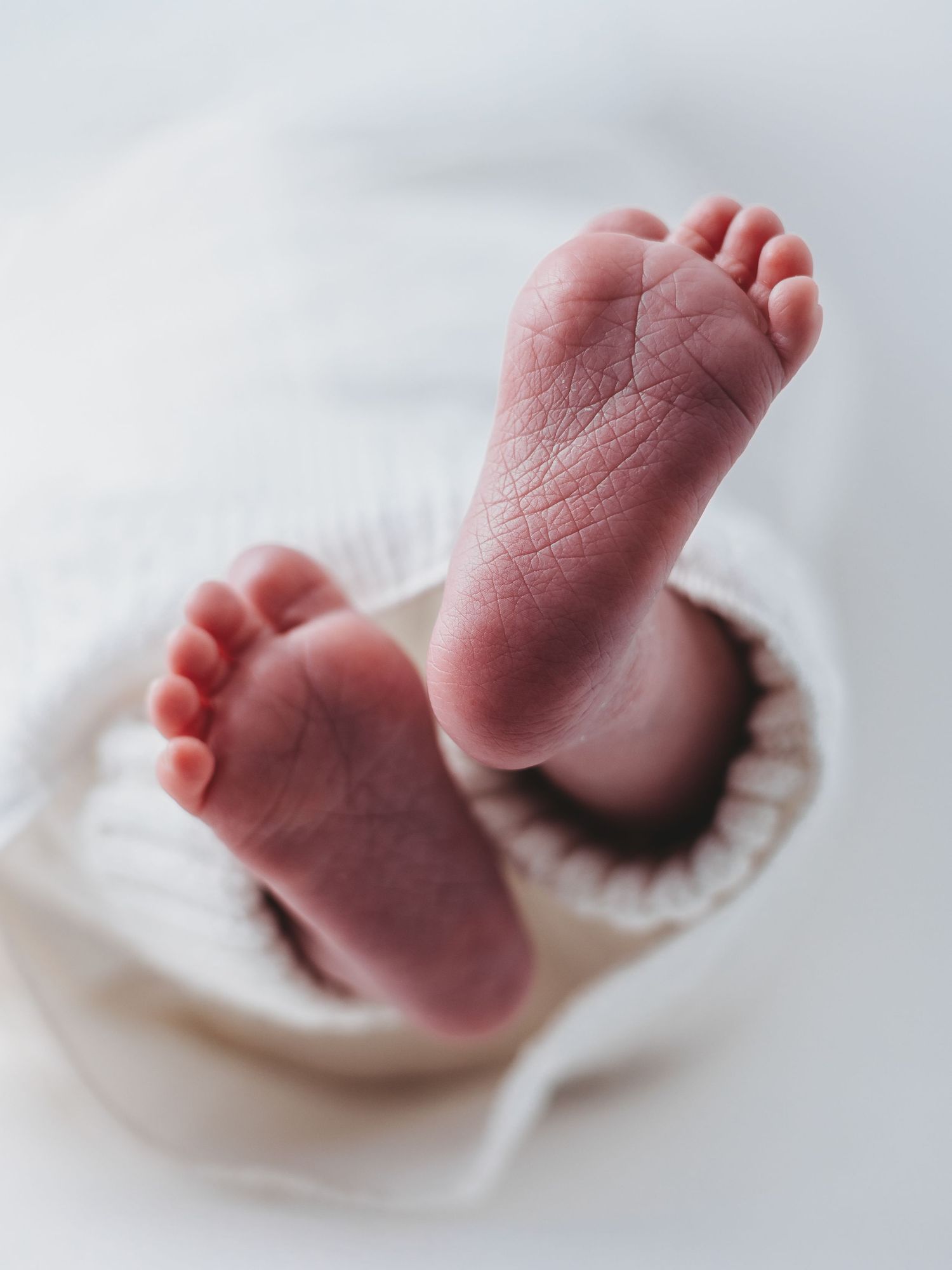 Close-up photos of tiny newborn baby feet against white fabric showing different angles and positions.