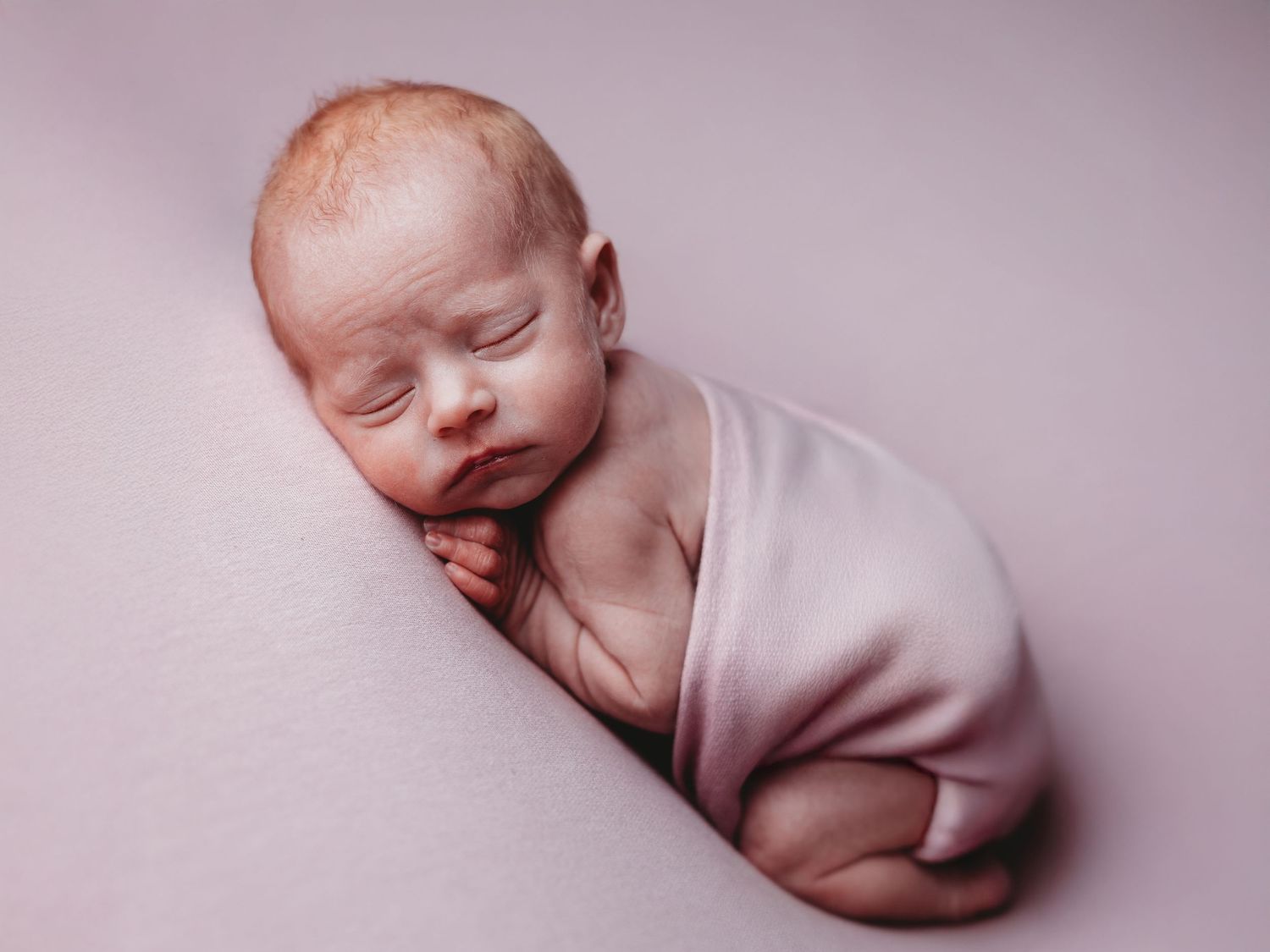 A series of black and white newborn baby photos showing peaceful sleeping poses on a soft backdrop.