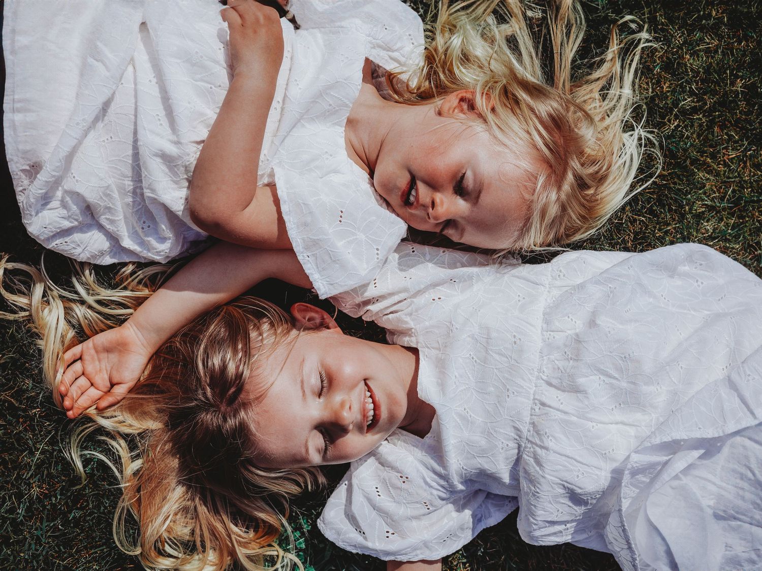 A series of candid photos showing people lying on grass wearing white clothing in a dreamy outdoor setting.