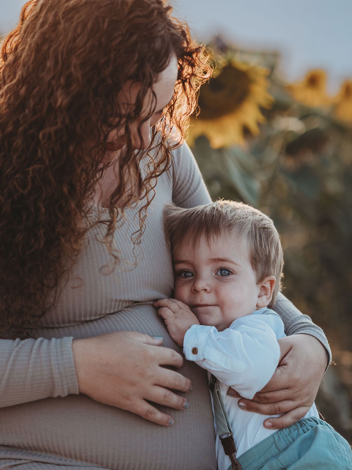 A tender moment between parent and child in a sunflower field at golden hour, with gentle embraces and soft lighting.