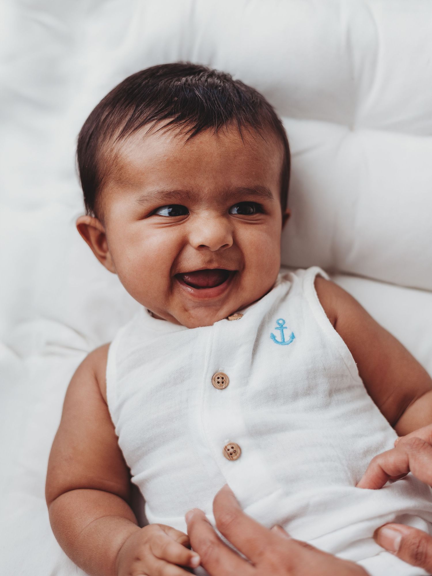 A collection of shots showing a smiling baby in white clothing against white bedding.