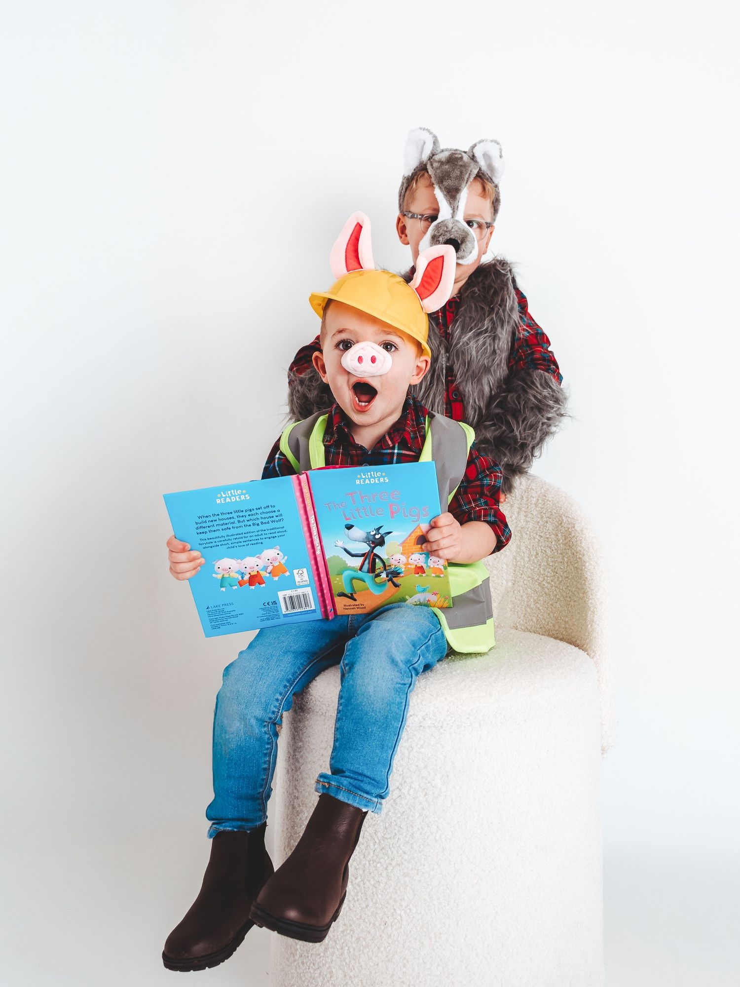 Two children in costume as the Three Little Pigs and Big Bad Wolf reading a storybook together.