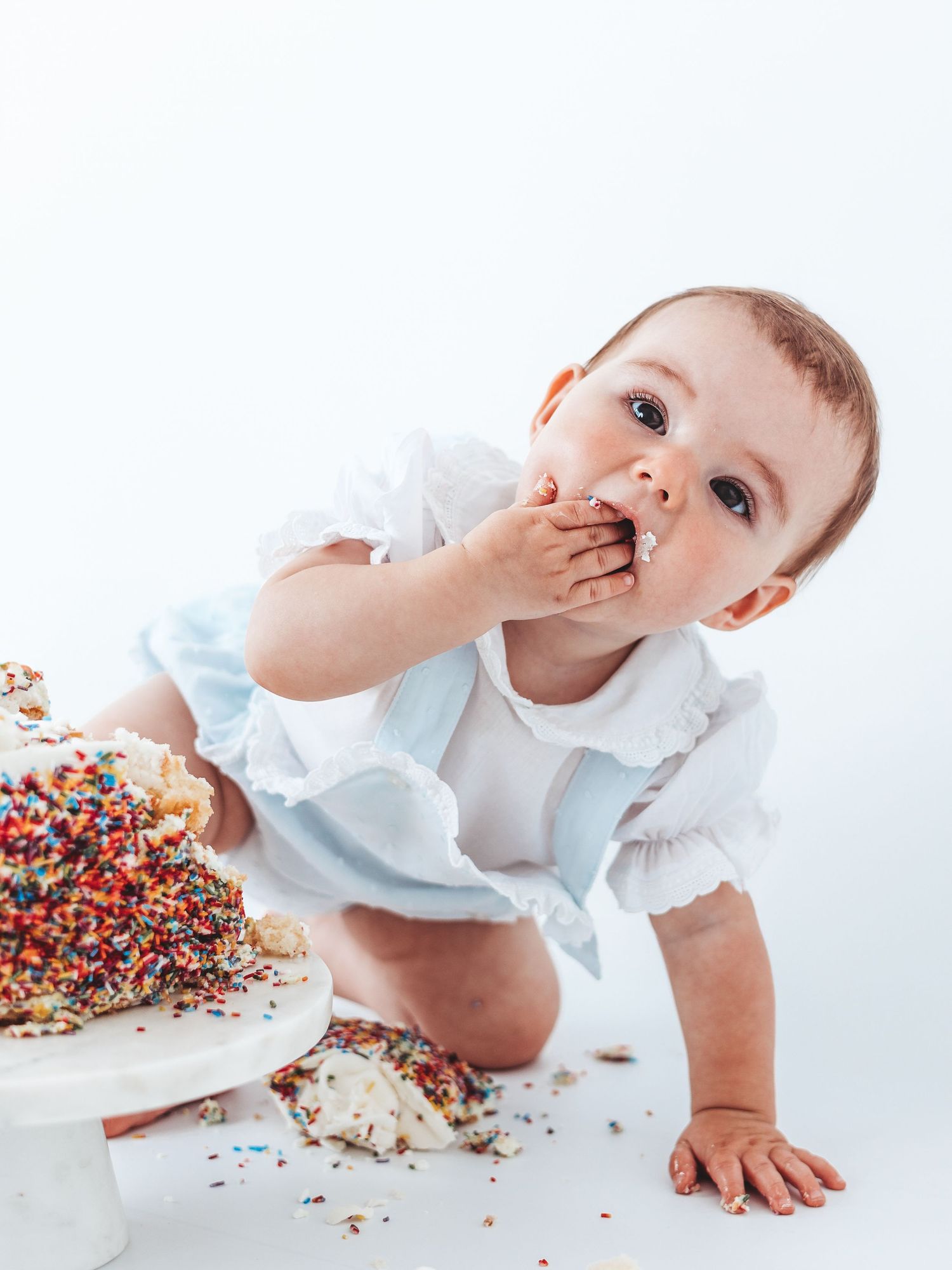 Baby girl eating birthday cake during a cake smash photoshoot.