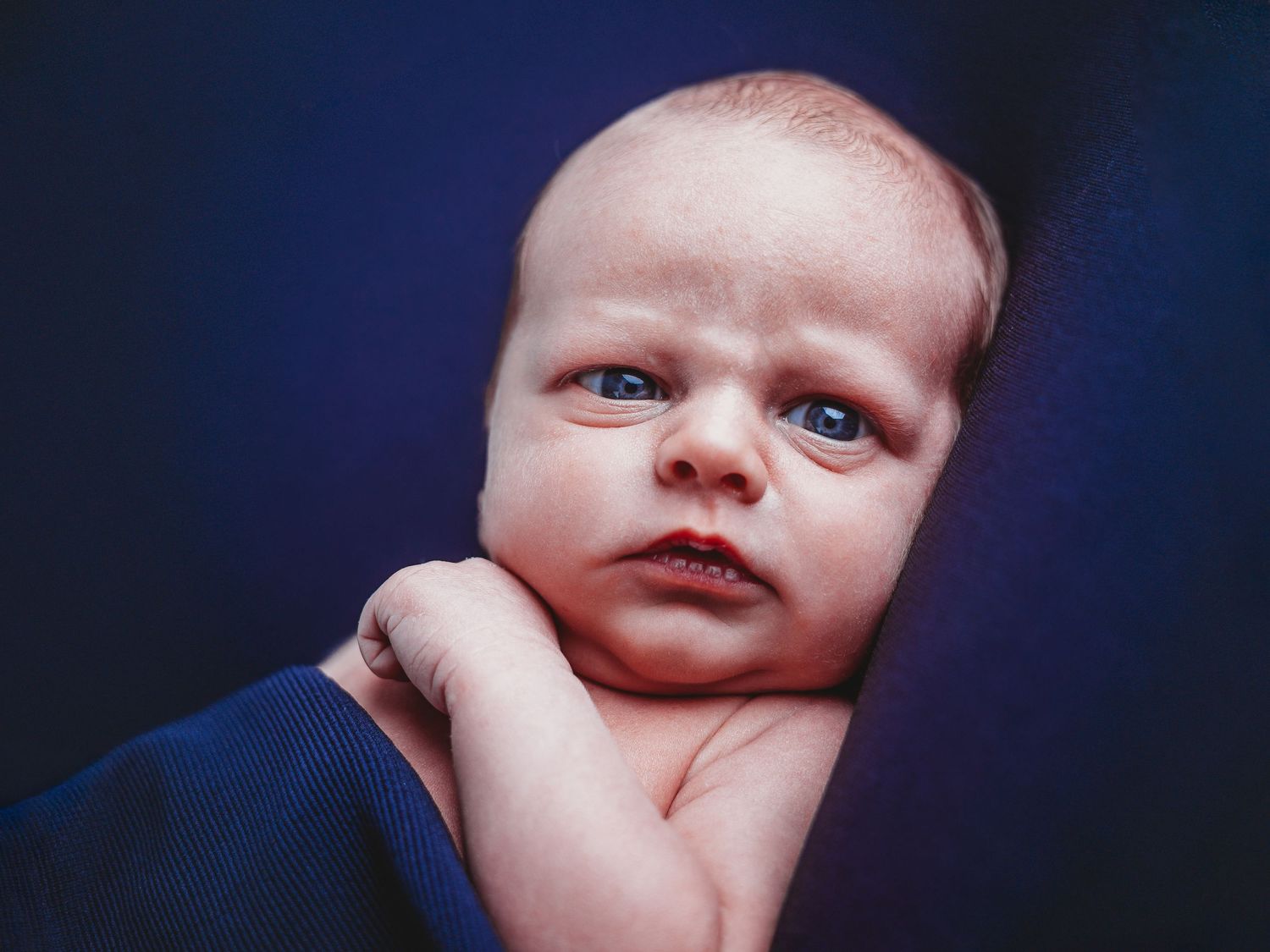 A series of four close-up portraits of a baby's face against a dark blue background.