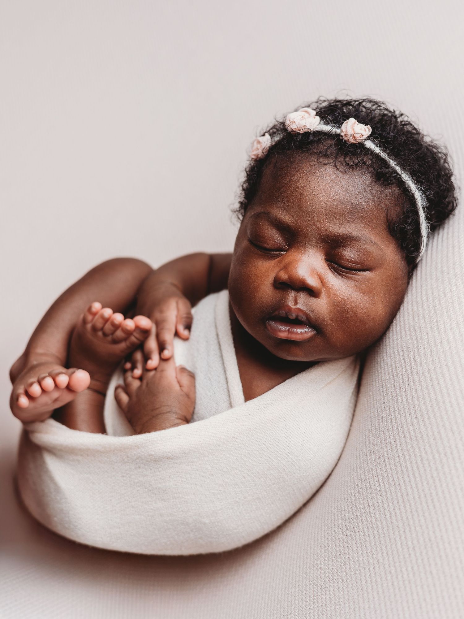 A sleeping baby wrapped in white blanket shown in four peaceful poses against a light background.