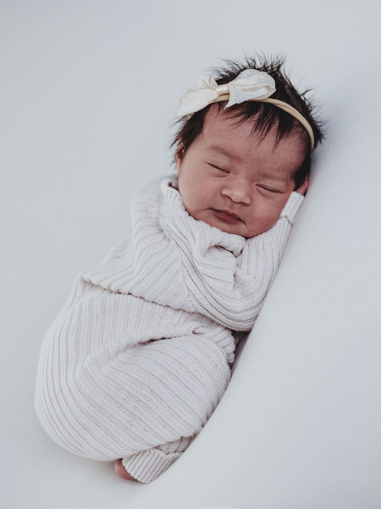 A sleeping newborn baby swaddled in white fabric shown from four different angles against a light background.