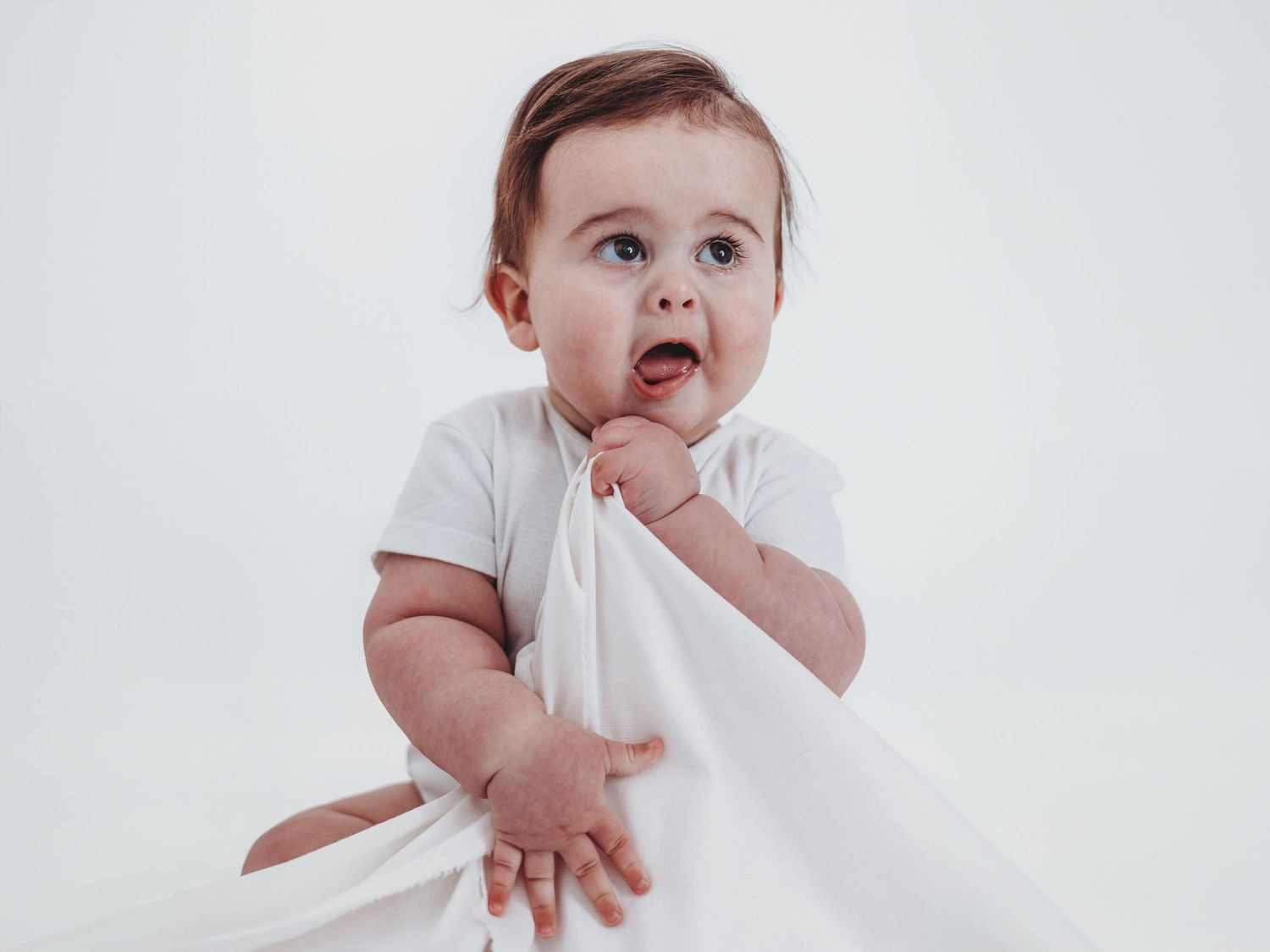 A series of four baby photos showing different facial expressions and hand gestures against a white background.