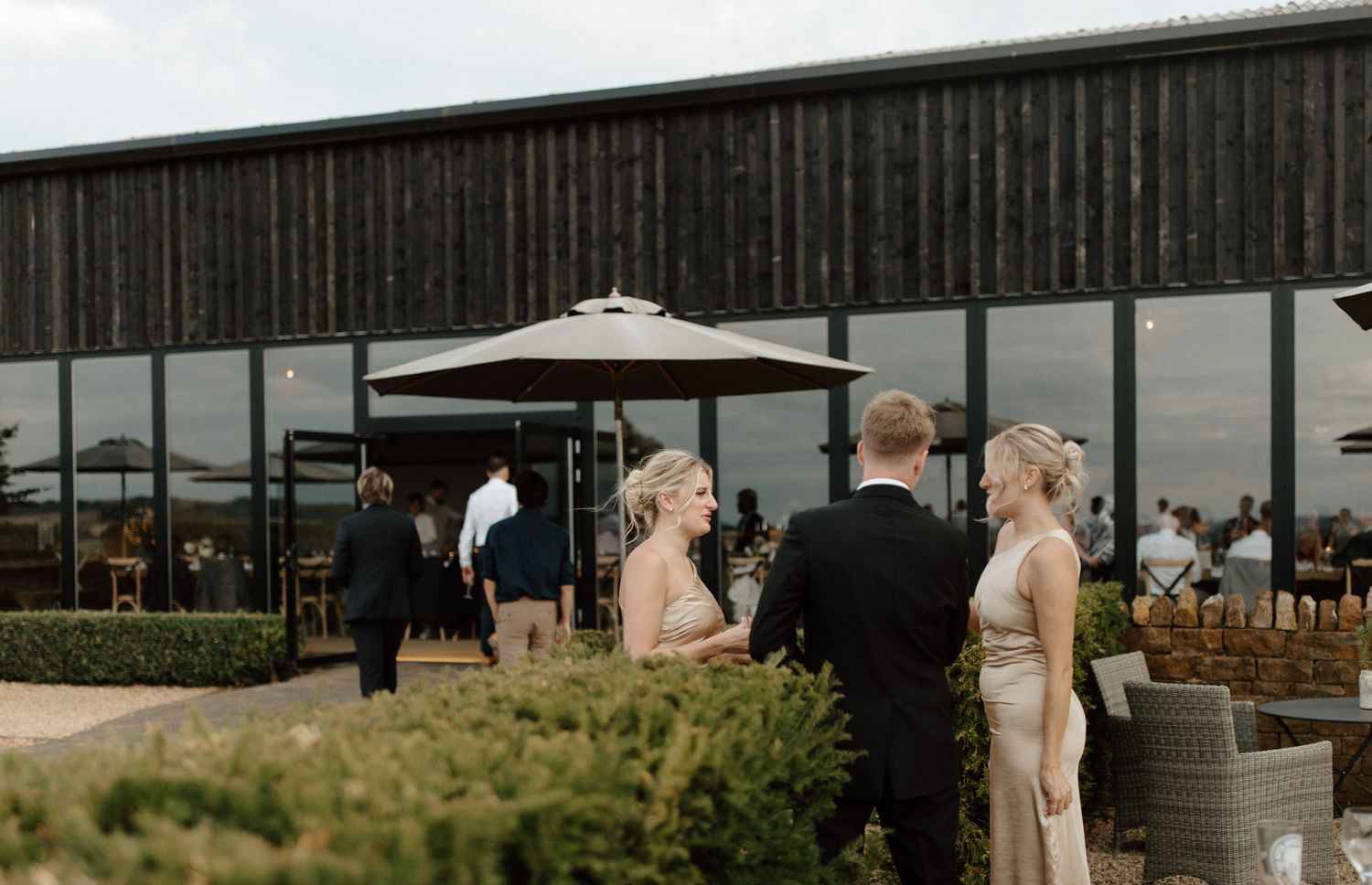 Modern barn-style venue with dark wood exterior and outdoor seating area.