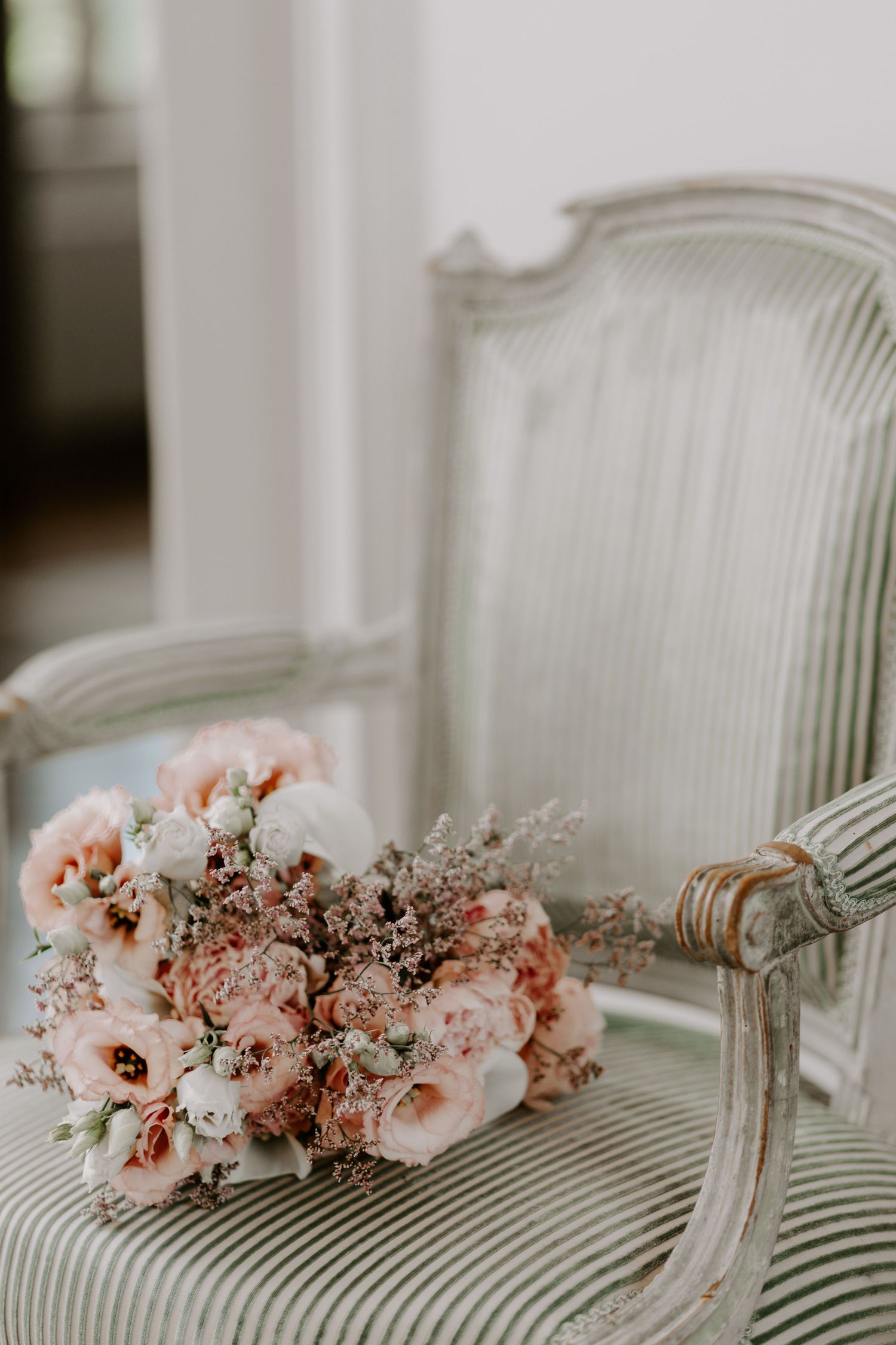 Delicate pink and white floral arrangement on a classic striped armchair.