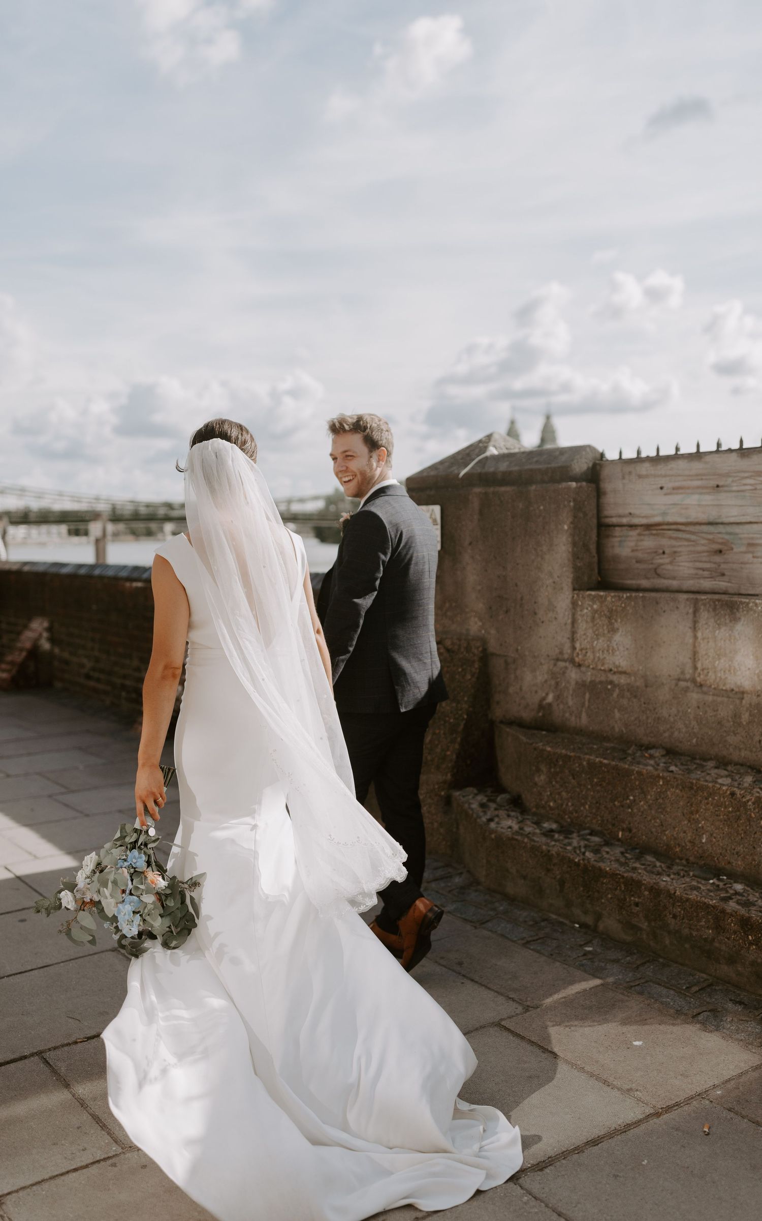 Wedding couple on rooftop with bride in flowing white dress and long veil.