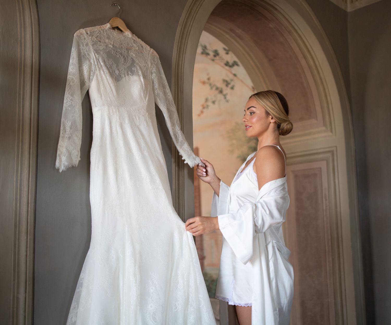 Wedding dresses hanging in an elegant arched doorway with natural light.