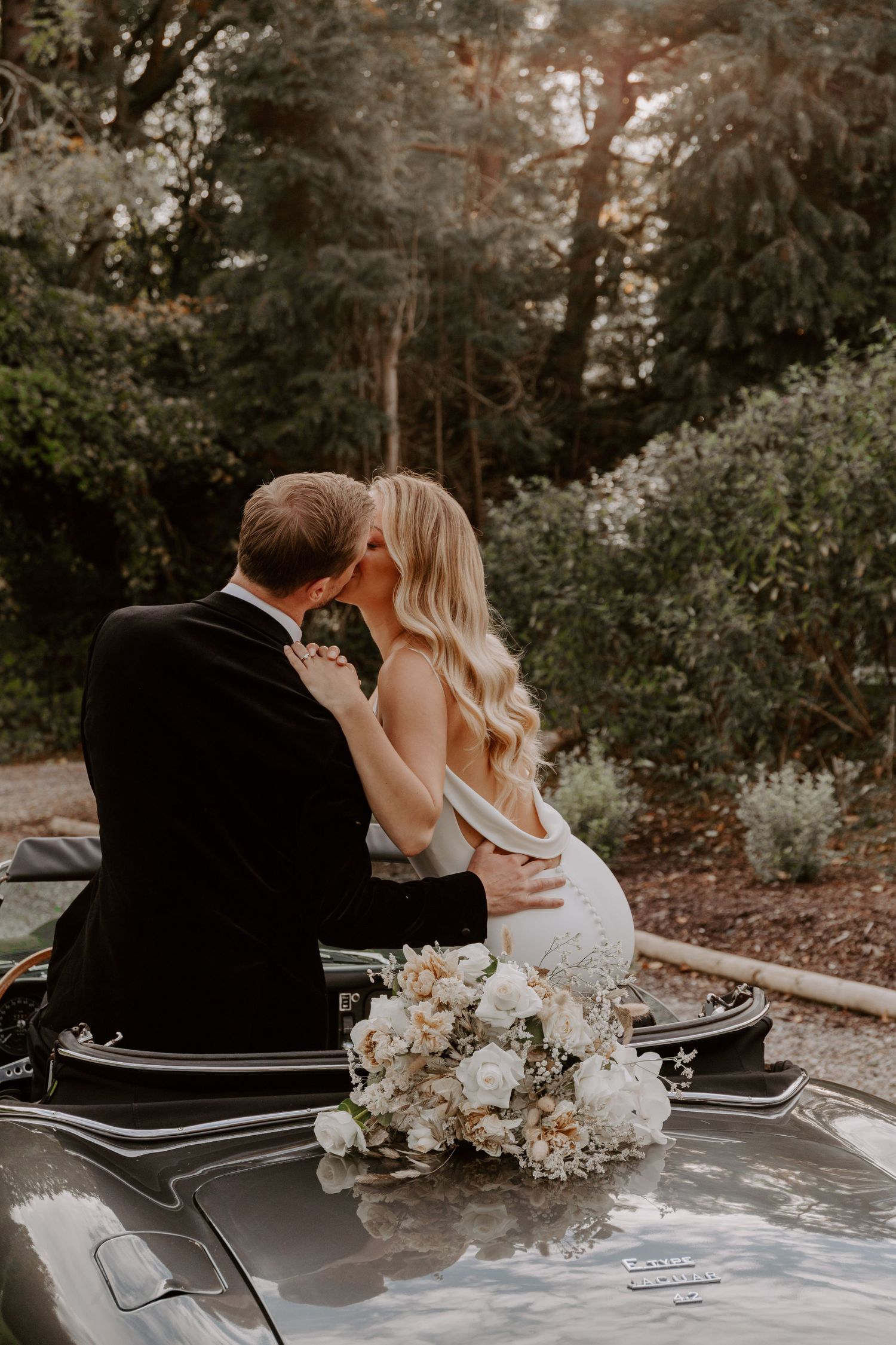 Romantic moment captured on vintage car with white floral decorations.