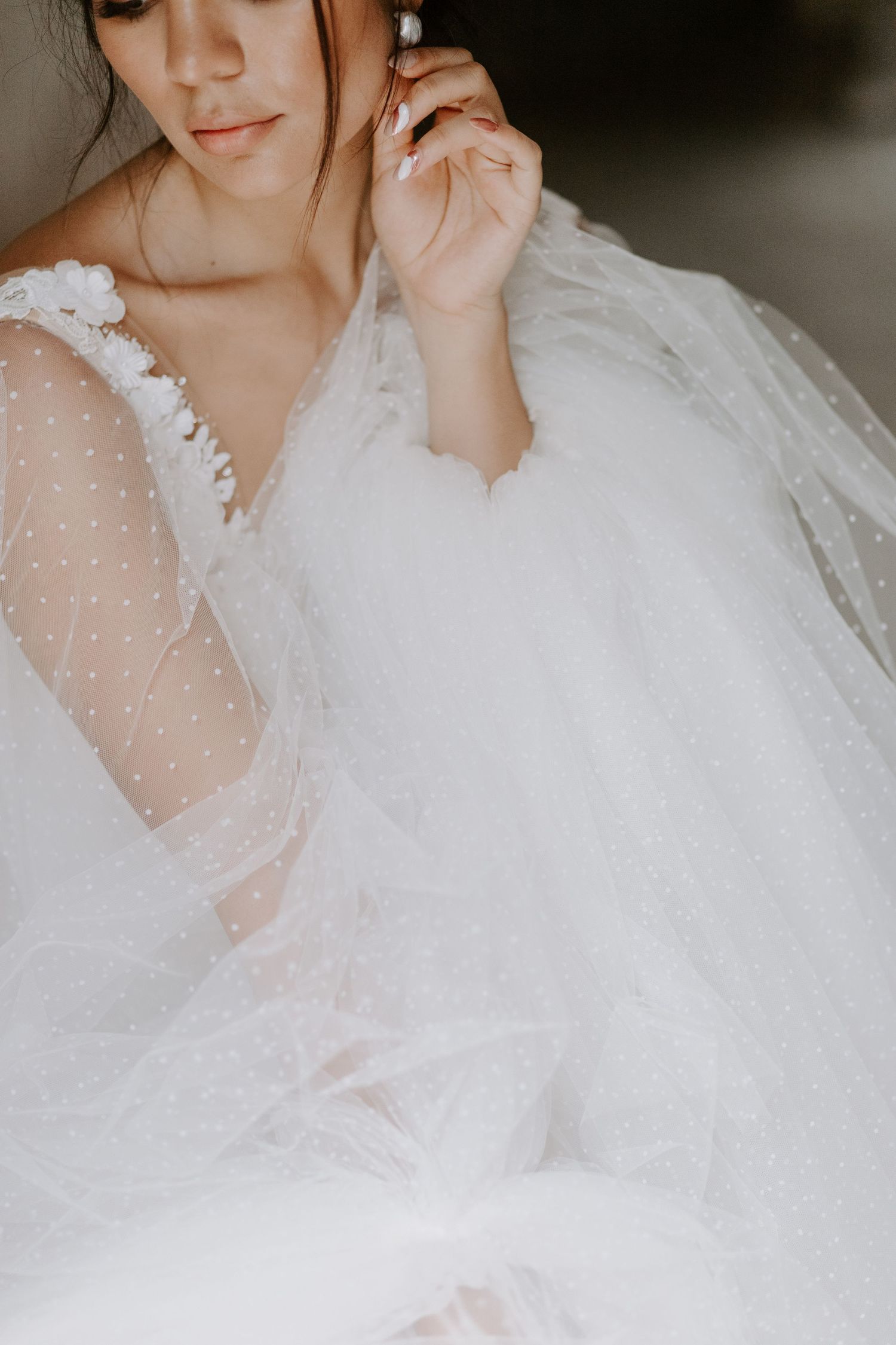 Close-up details of a romantic wedding dress with delicate polka dot tulle fabric.