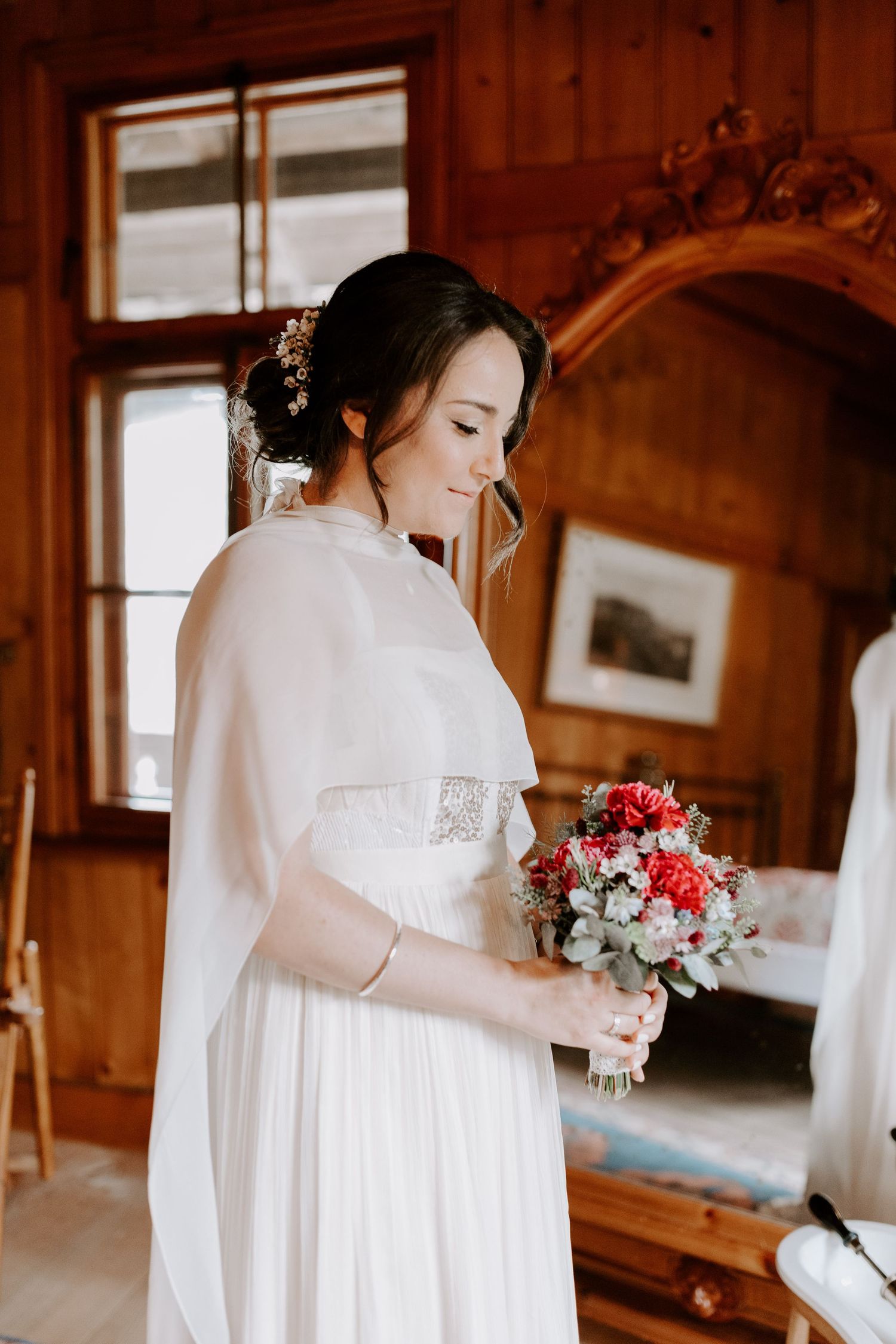 A delicate bouquet of pink and white flowers held against a flowing white dress.
