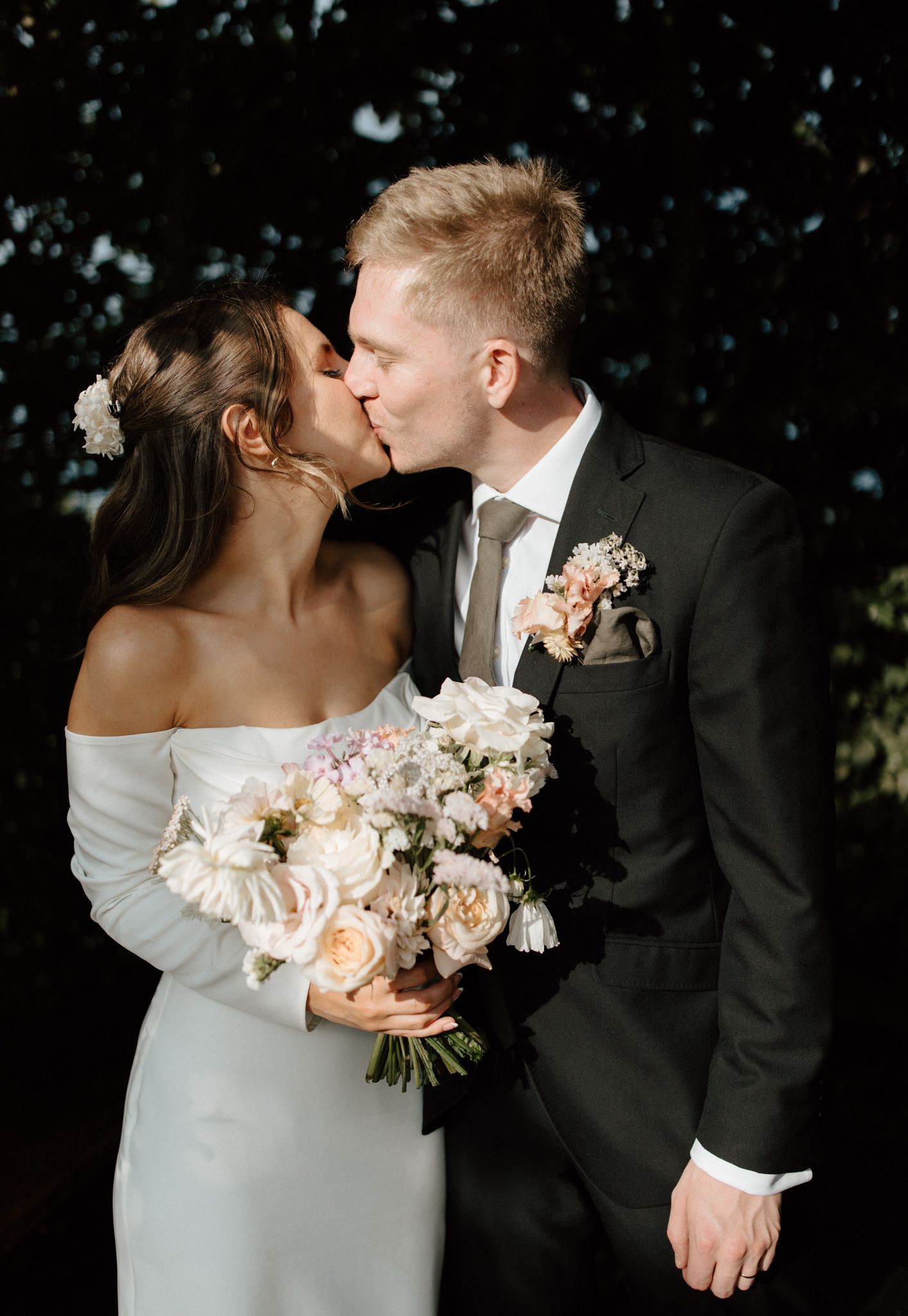 Romantic wedding moment with soft pink floral bouquet against dark background.