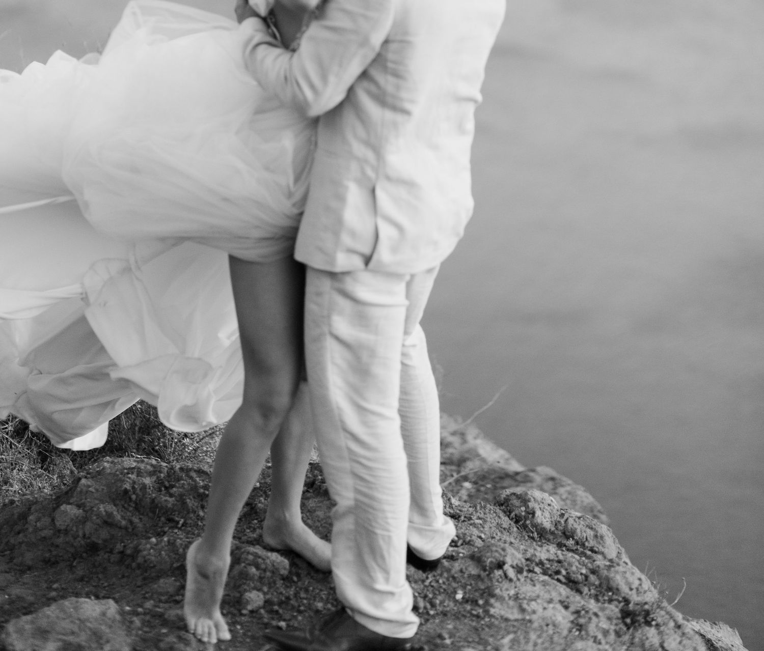 Black and white wedding photo capturing an intimate moment on a cliff in Santorini