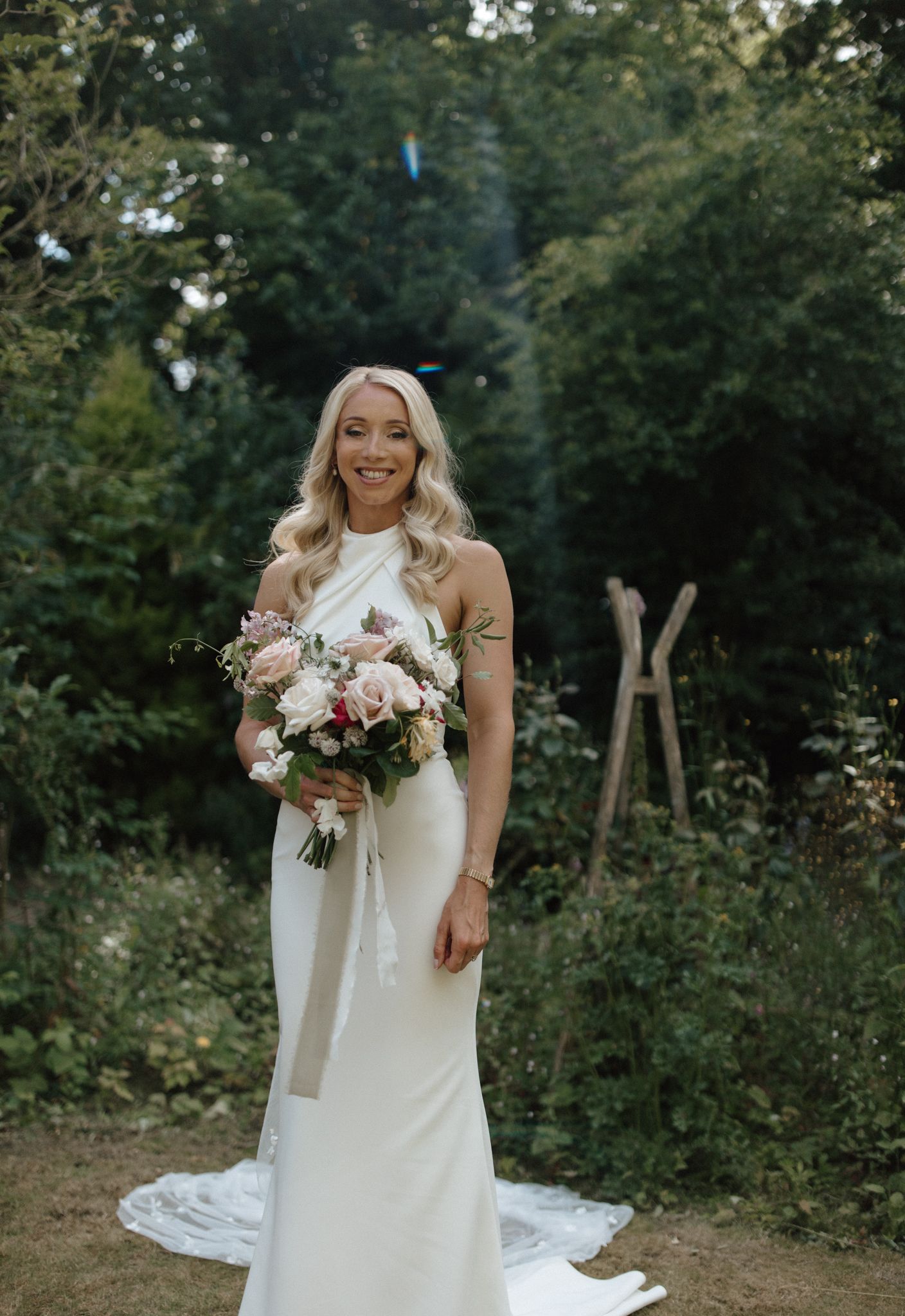 A stunning bridal portrait in a flowing white wedding dress against a lush garden backdrop.