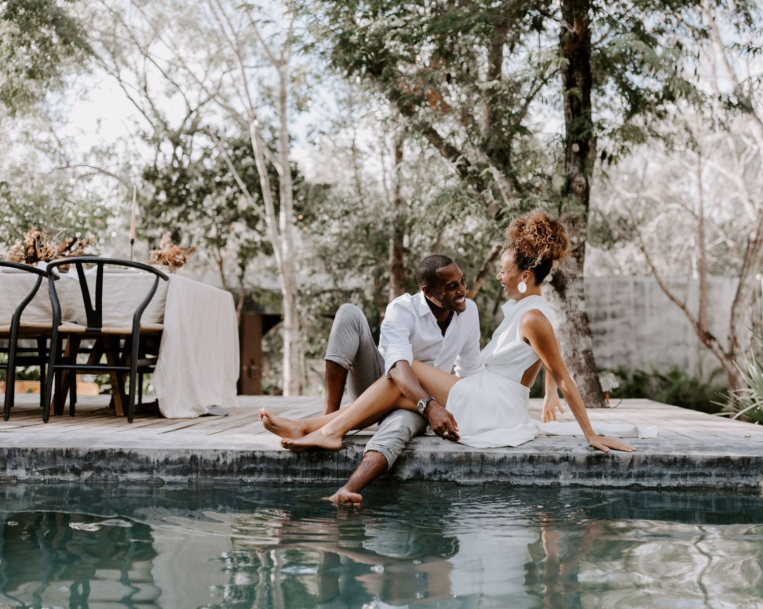 Couple relaxing by a serene swimming pool surrounded by lush tropical vegetation.