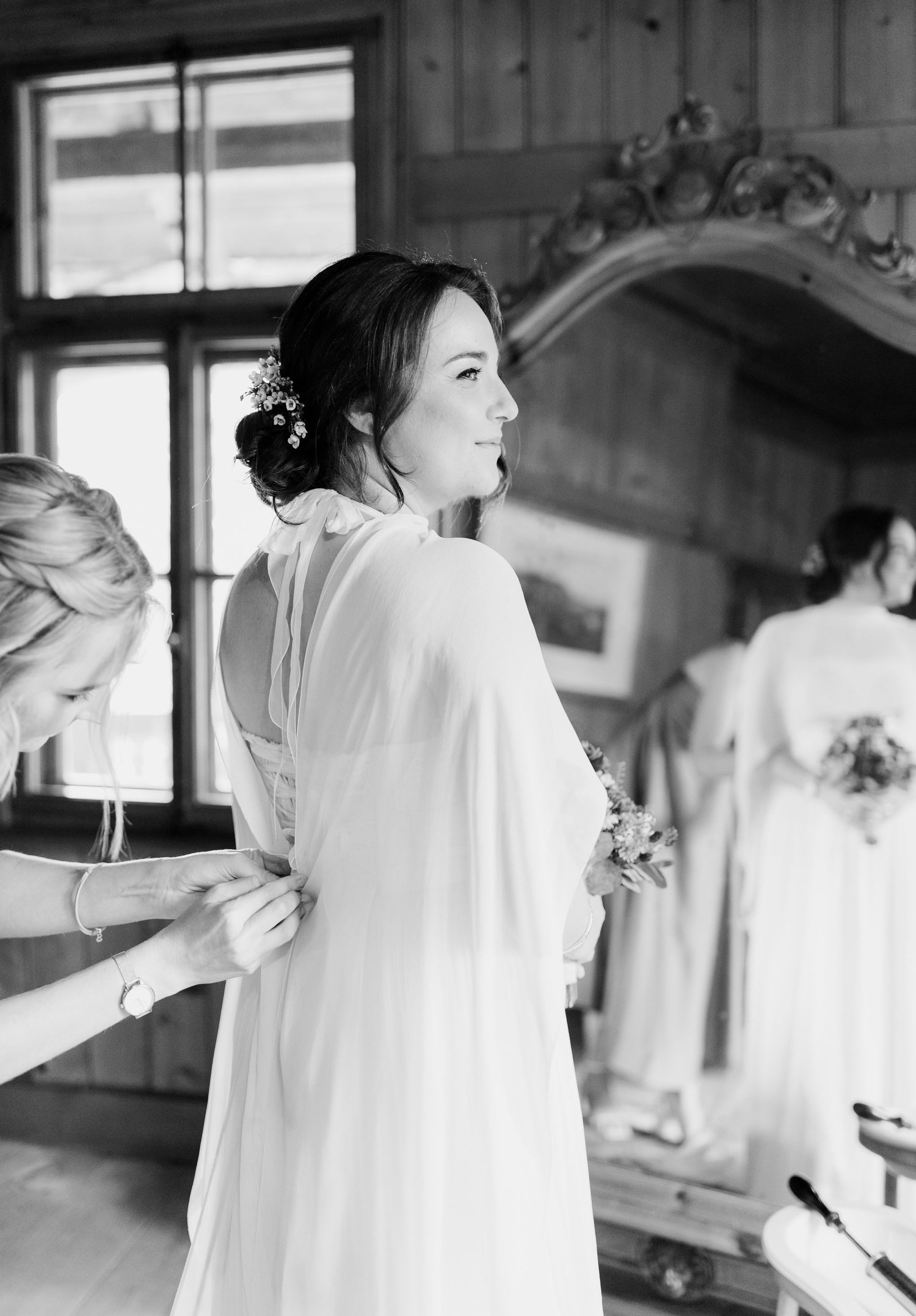 Black and white photo of wedding preparation in a rustic wooden room.