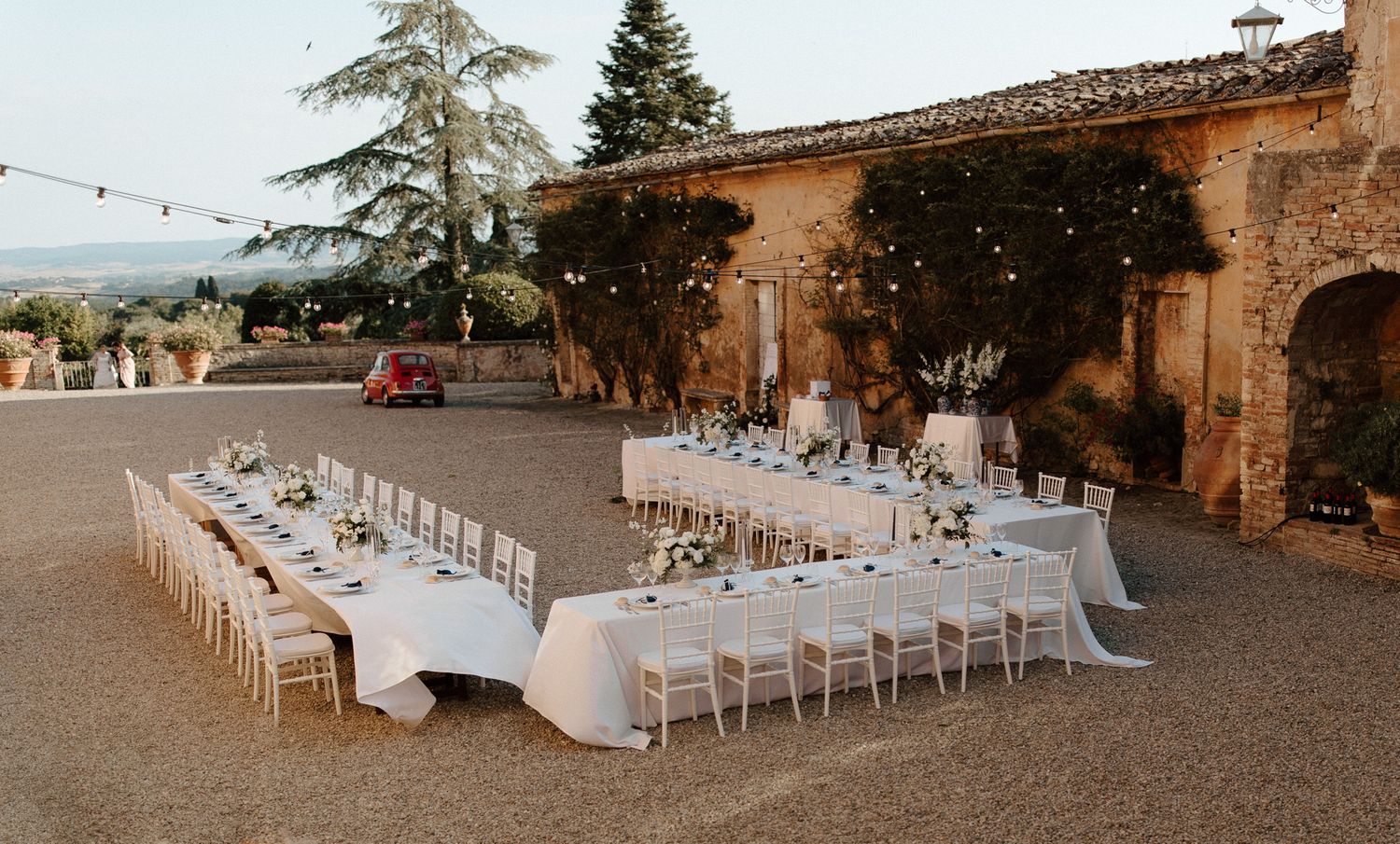Rustic outdoor wedding reception setup with long tables at a Mediterranean villa.