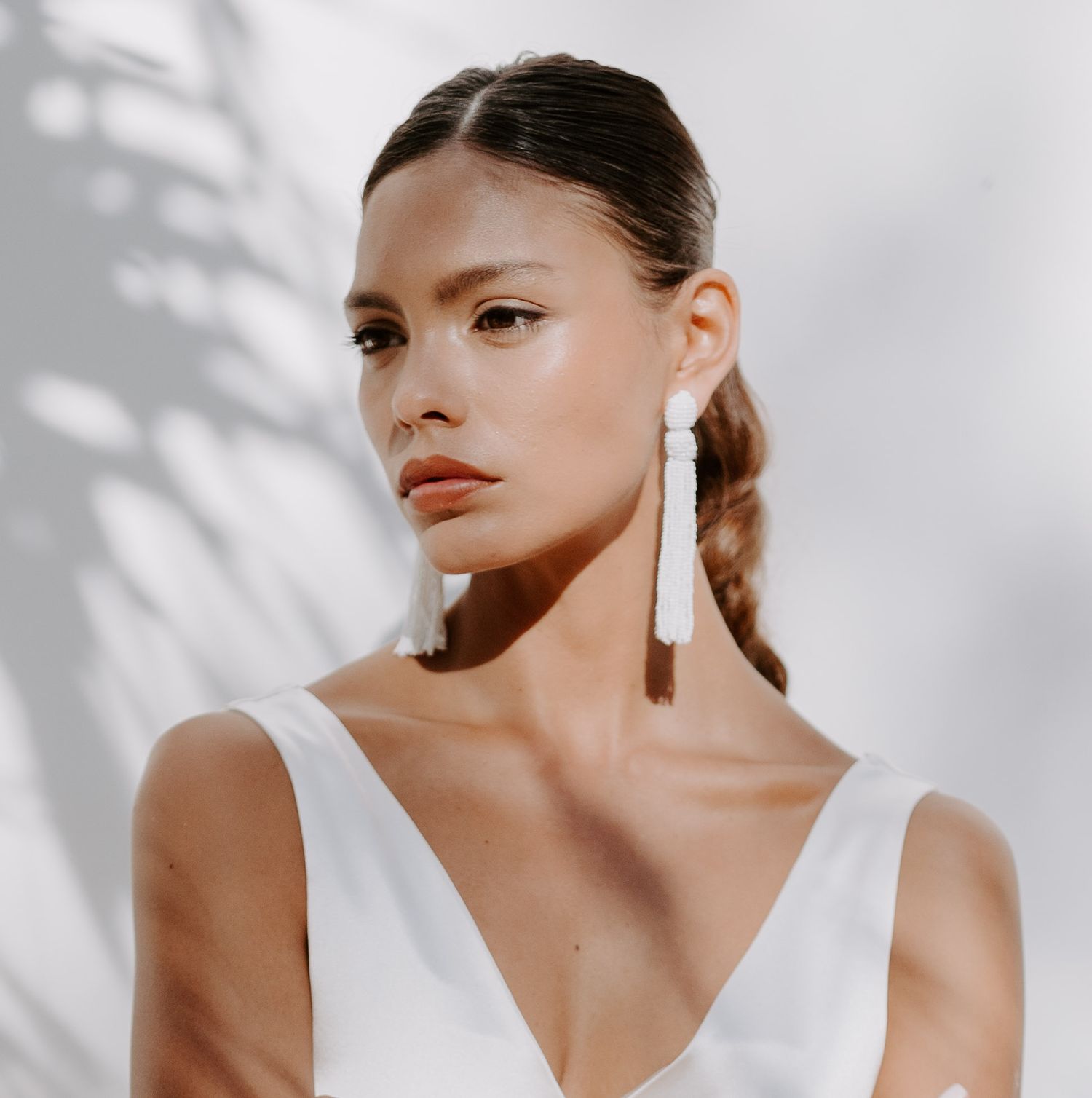 Artistic portrait in white against a light background with dramatic shadow play.