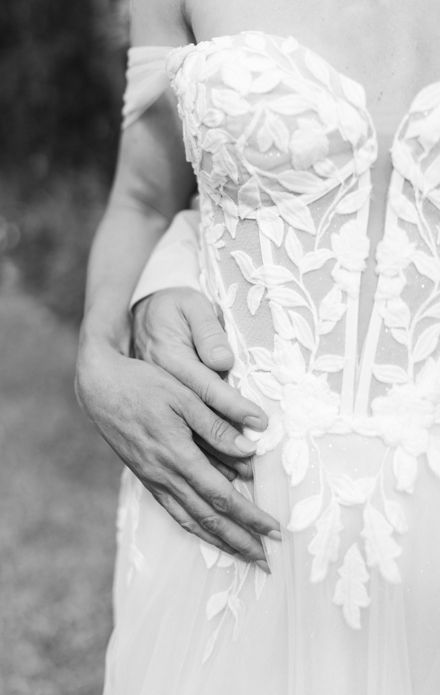 Close-up detail of delicate white floral lace on a wedding dress.