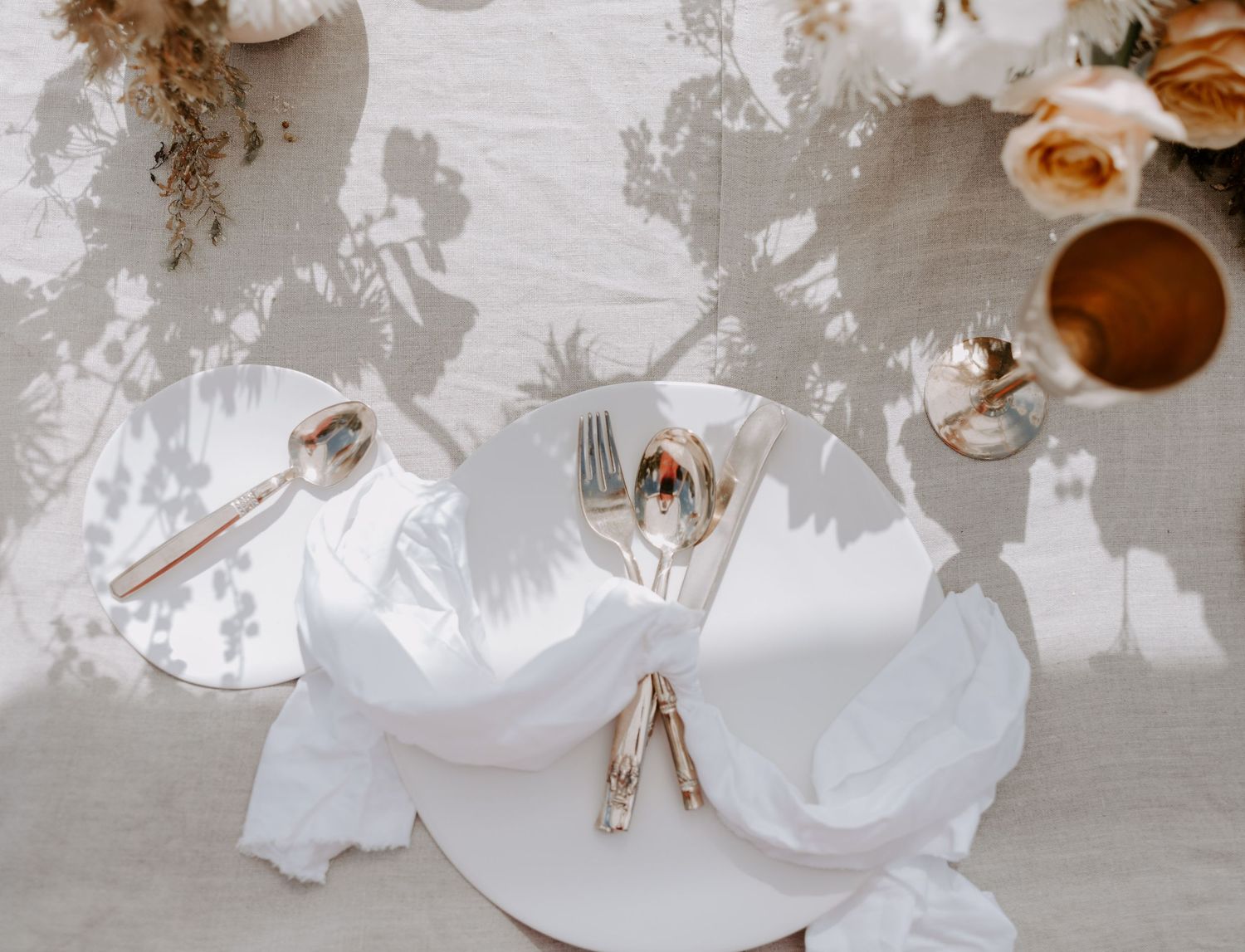 Elegant wedding table setting with white floral centerpieces and gold accents.