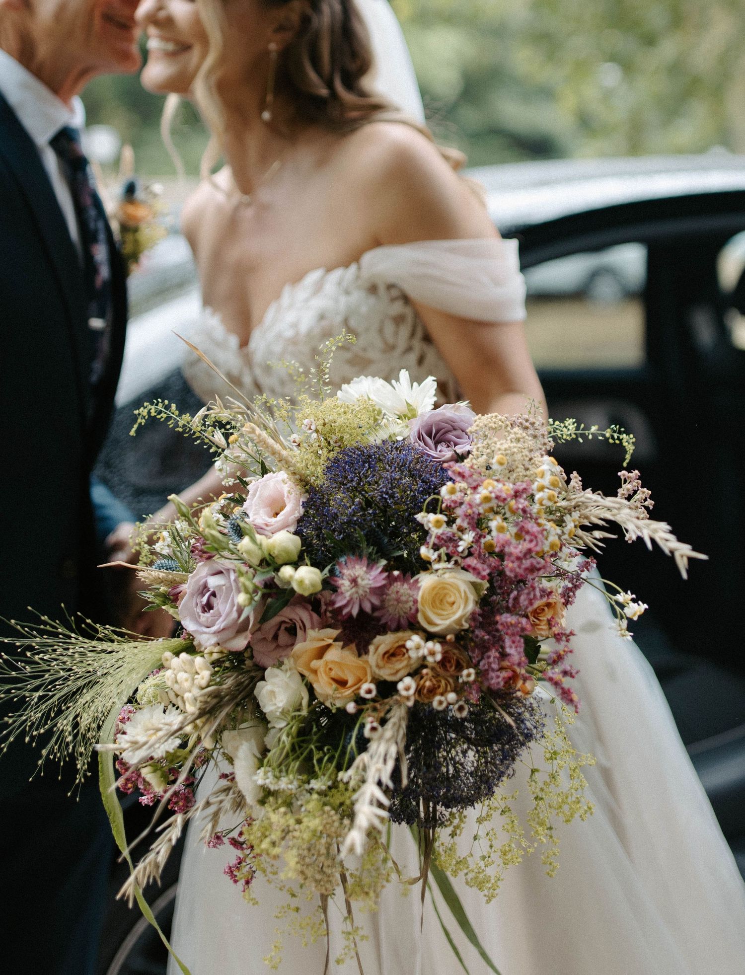 Stunning wedding bouquet with purple, pink and cream flowers in wild arrangement.