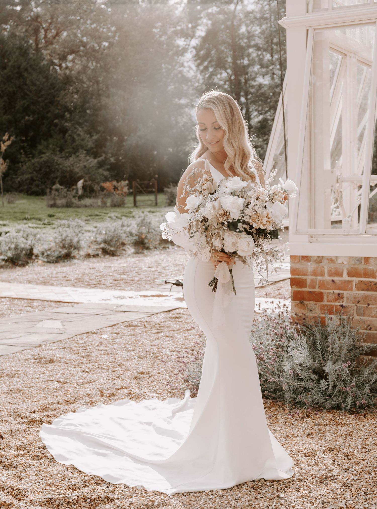 Romantic bridal portraits on gravel path with flowing train and floral bouquet.