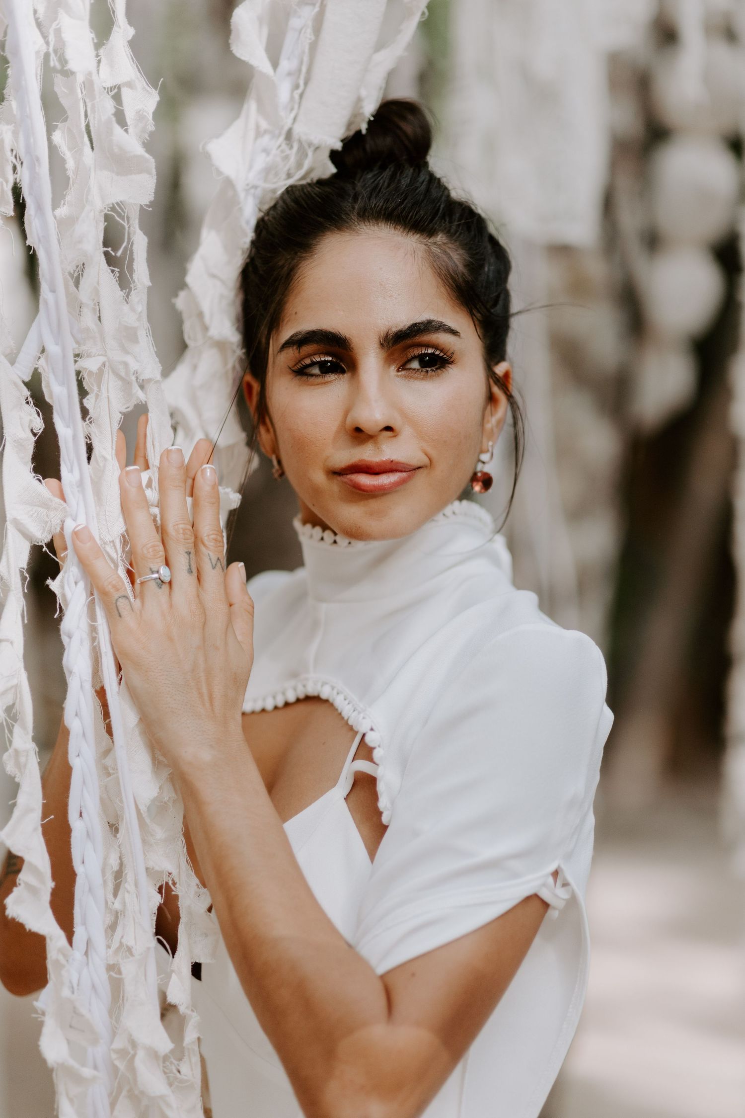 Artistic bridal portrait with white fabric draping and dramatic lighting.