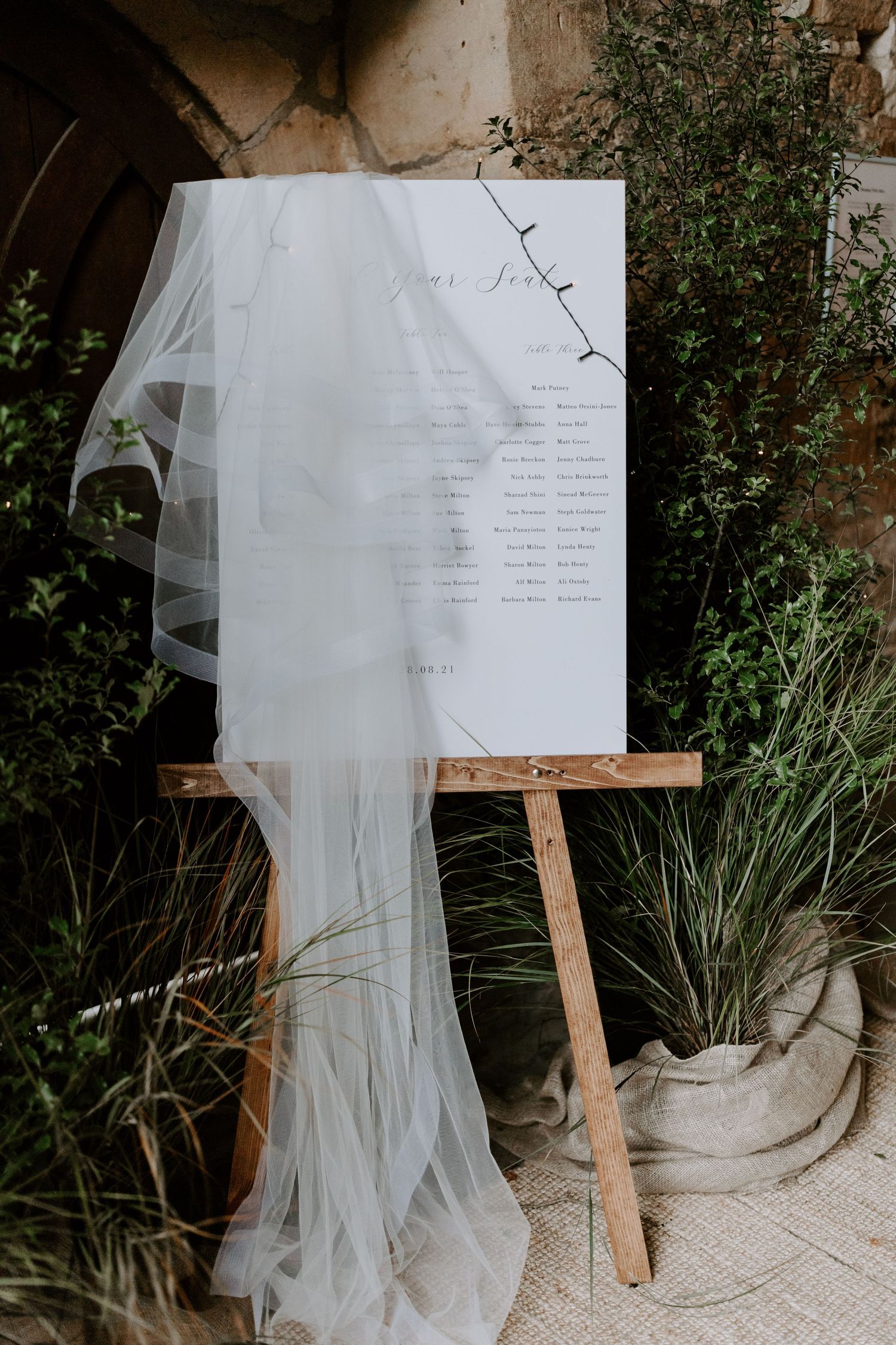 Wedding dress and veil displayed outdoors next to a wooden easel with signage.