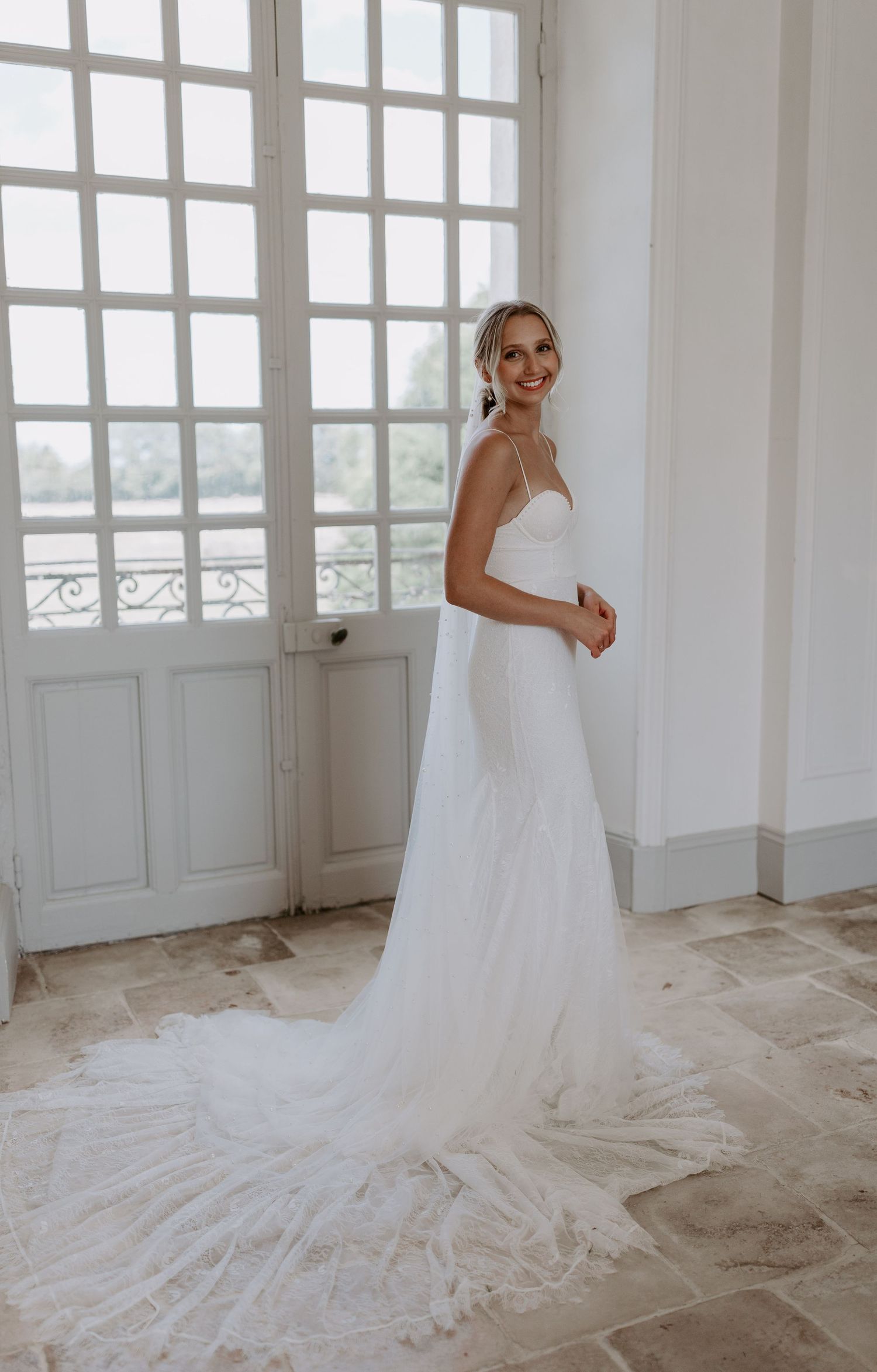Dramatic cathedral-length wedding dress train spread across a bright white room.