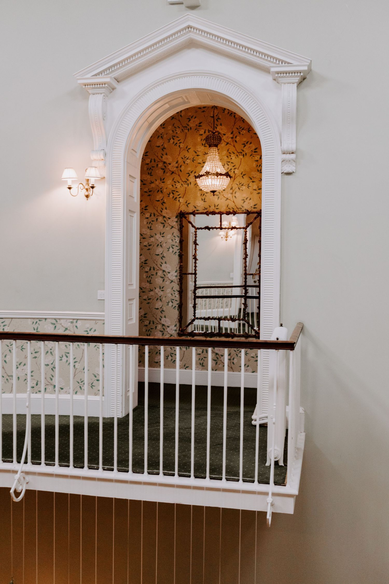 White ornate balcony railing with arched alcove and decorative wallpaper.