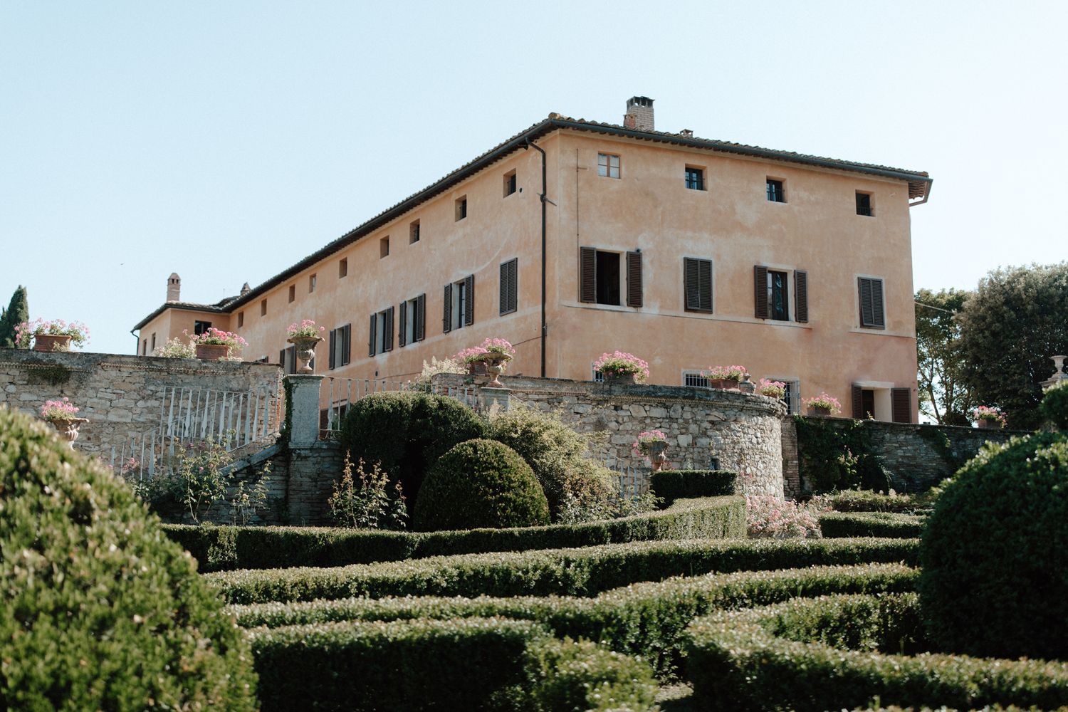 Tuscan villa with manicured gardens and terraced landscaping.