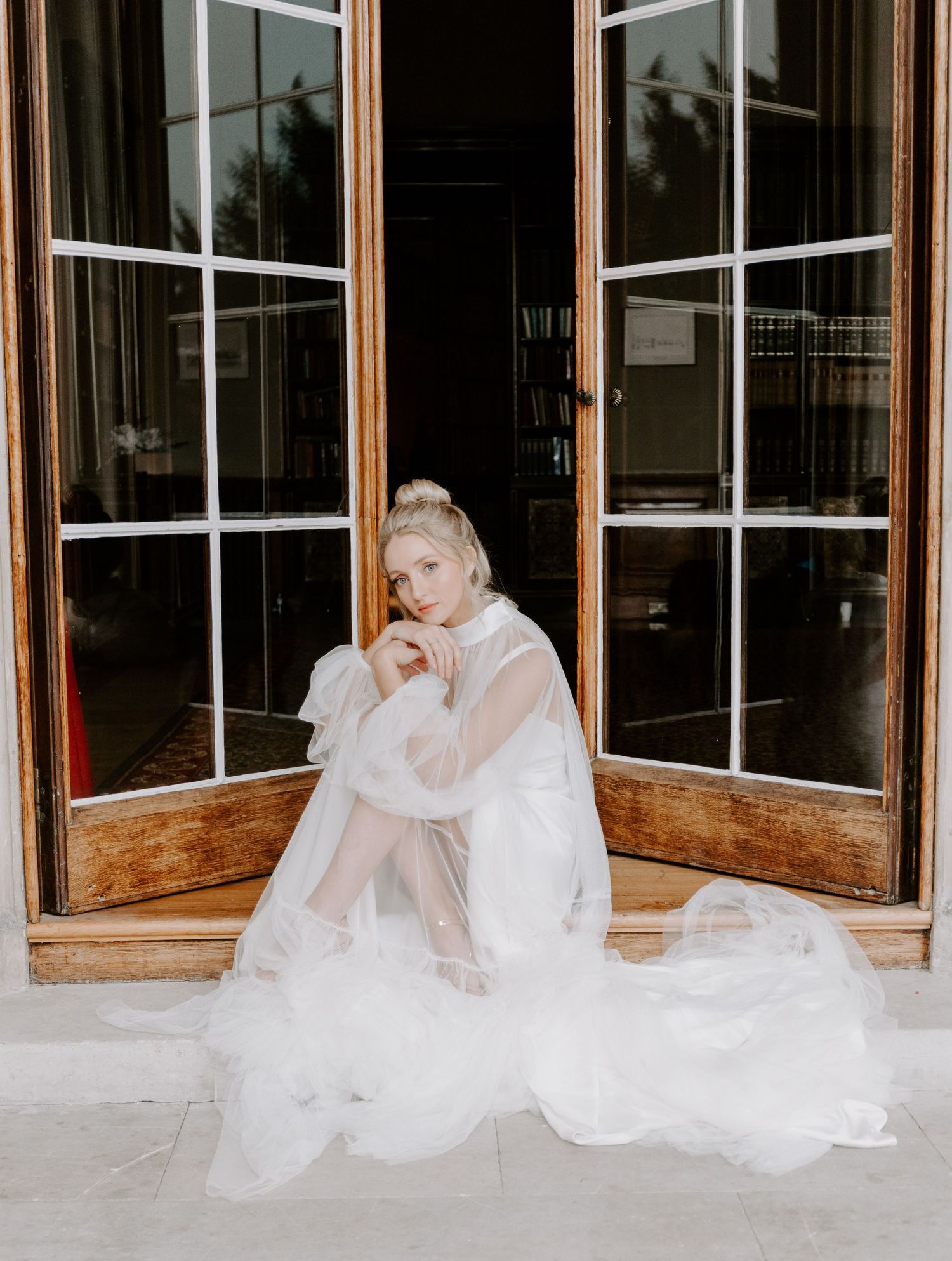 Ethereal bridal portraits through window panes showcase flowing white fabric and delicate natural lighting.