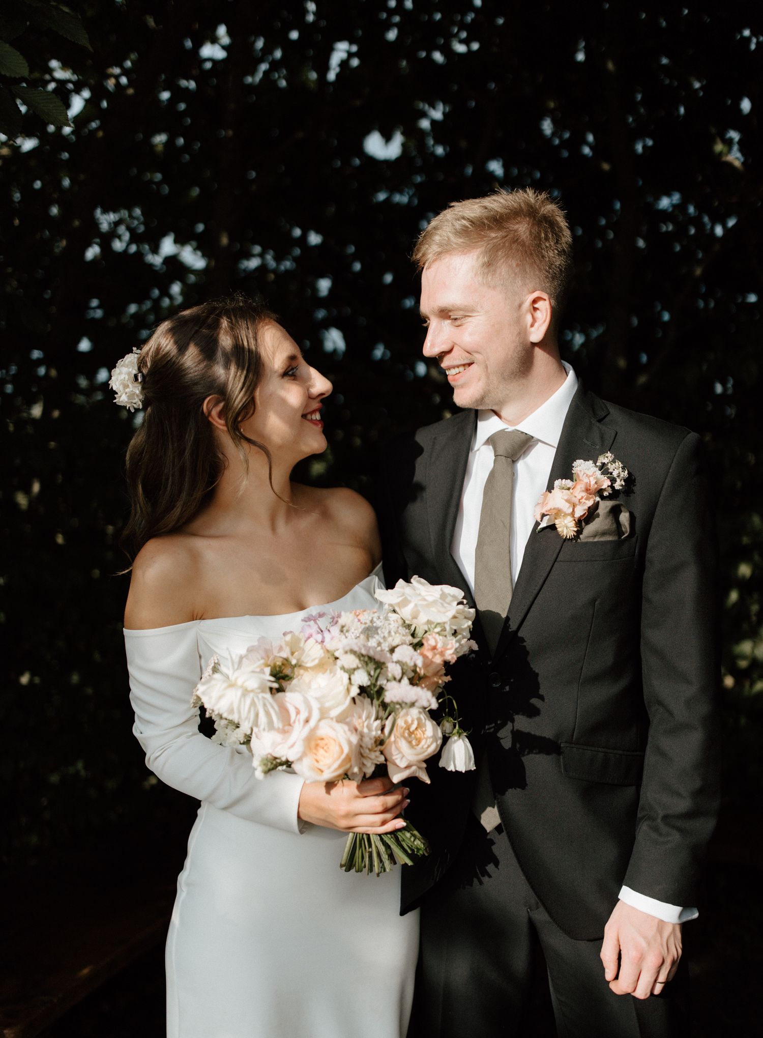 Intimate wedding portraits with a beautiful peach and white bouquet against a dark background.
