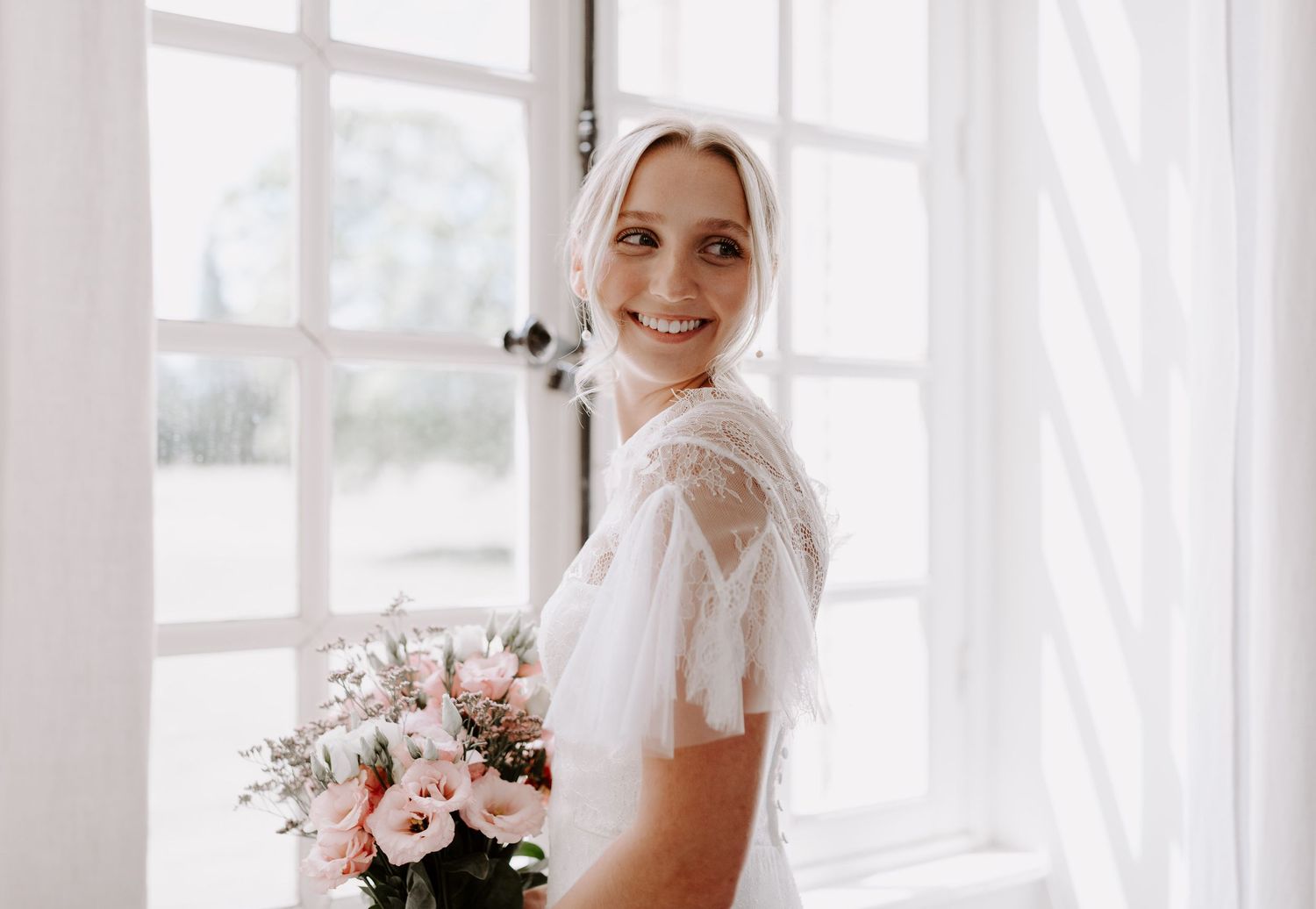 Ethereal bridal portrait with soft natural lighting and pink floral bouquet.