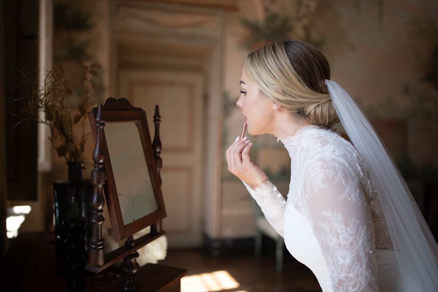 Elegant bridal portraits in vintage room with ornate wall murals and natural lighting.