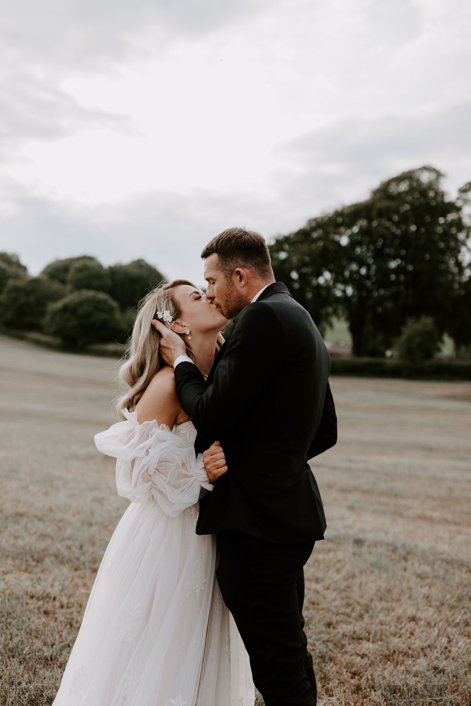 A romantic wedding moment captured in a moody outdoor setting.