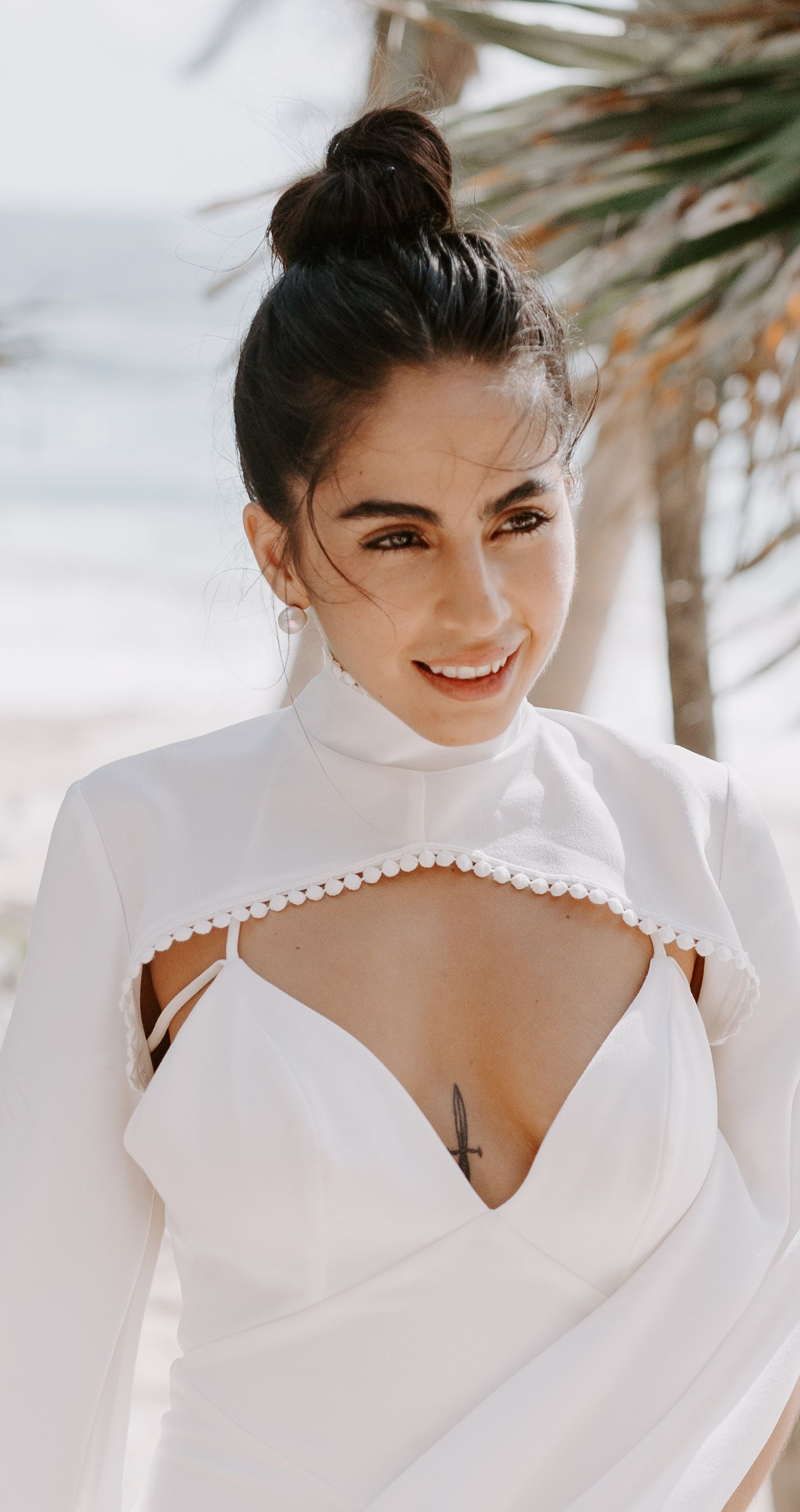 Elegant bridal portrait in a structured white gown against a beachy backdrop.